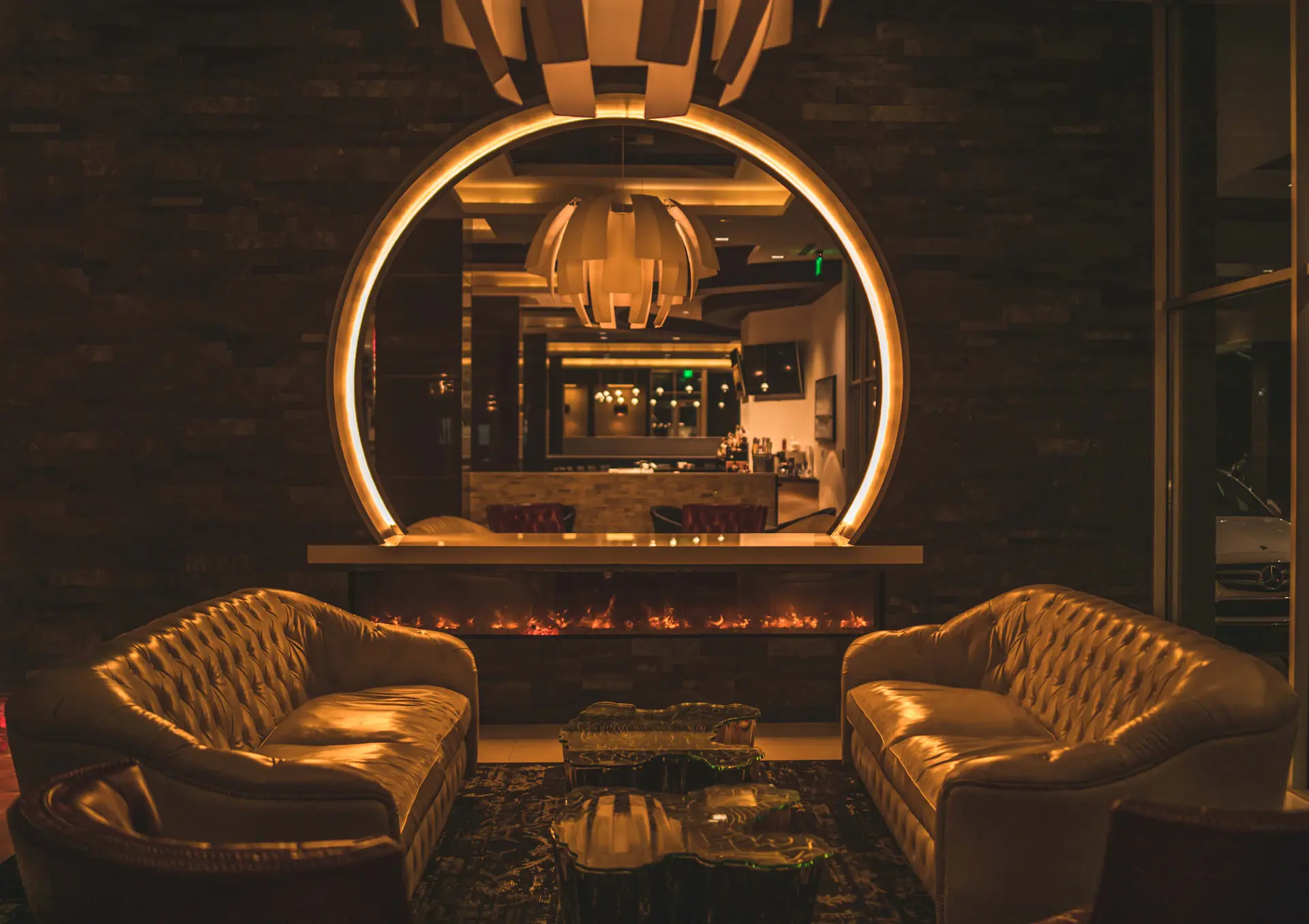 Dim, candlelit private salon with deep shadows and warm reflections
