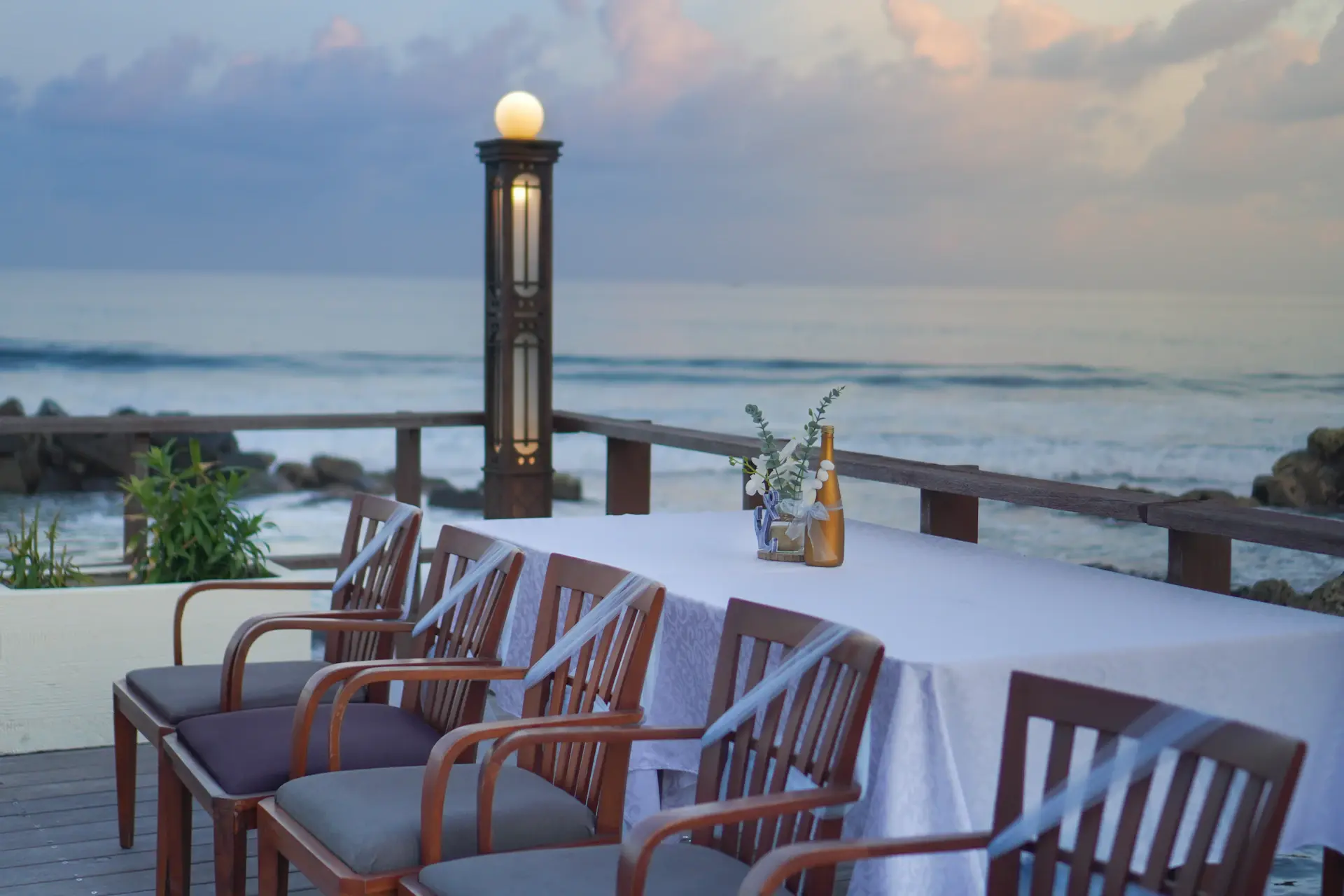 A terrace set for dinner above the sea