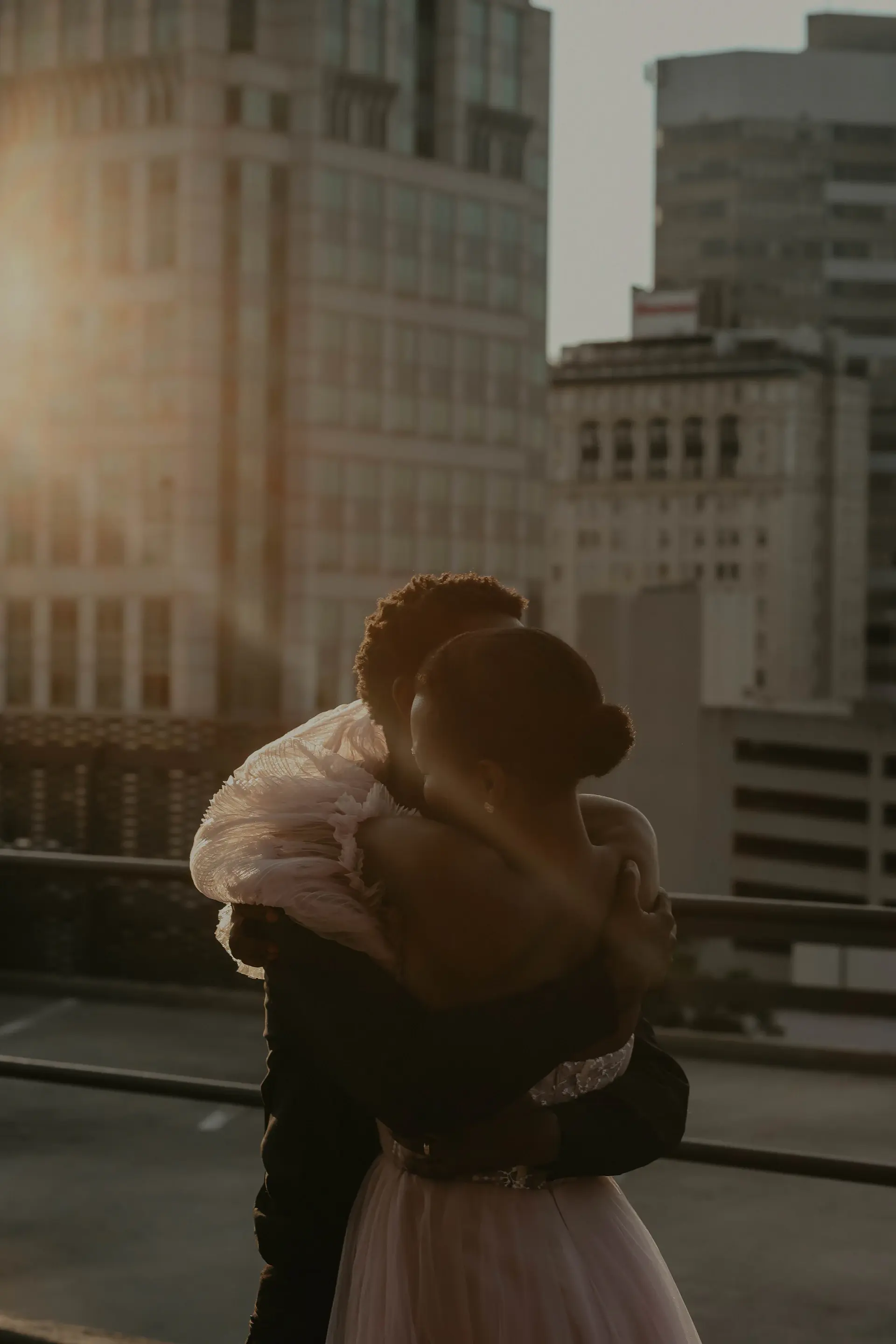A couple dancing on a rooftop at dusk with city lights behind
