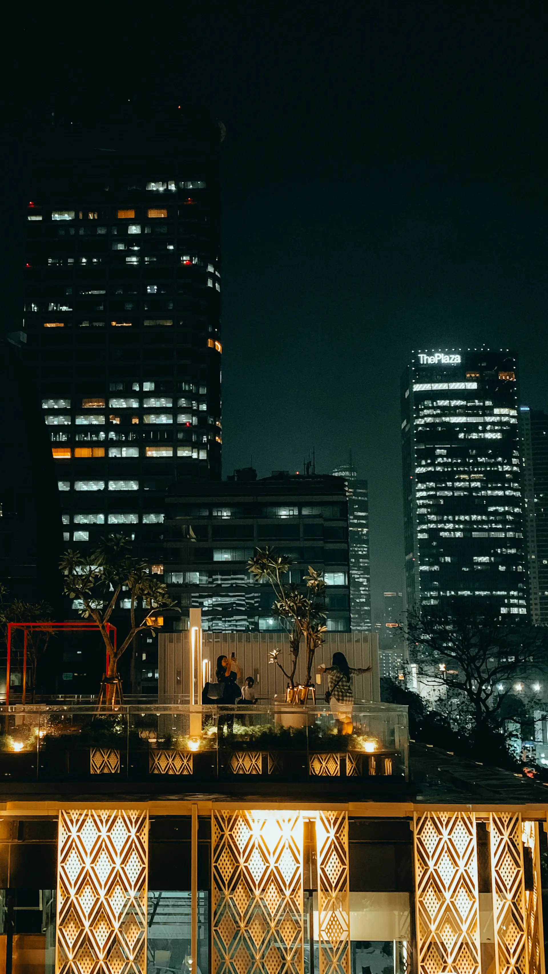 A rooftop pavilion overlooking a glittering city skyline at dusk