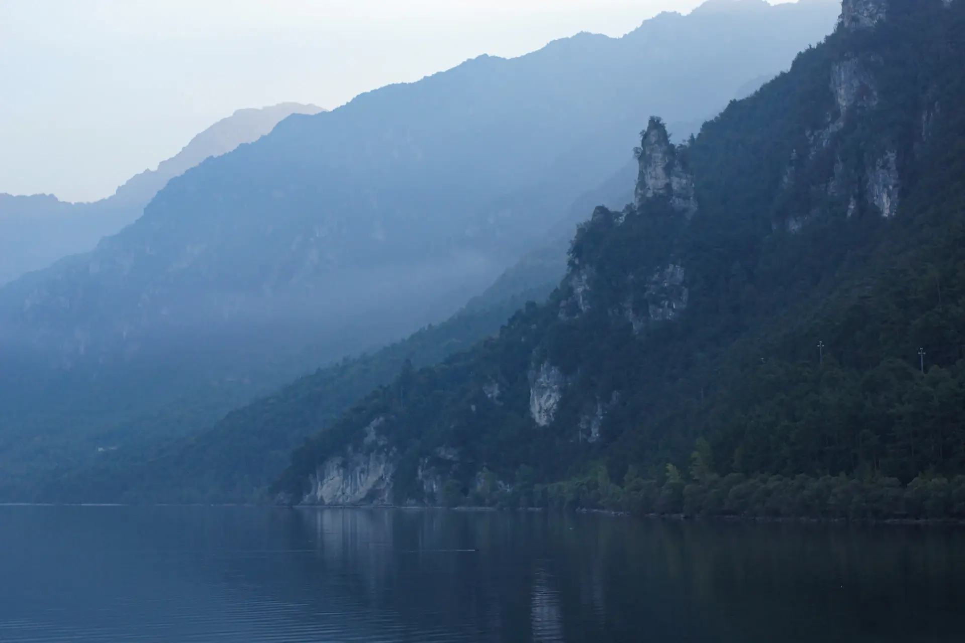 Soft morning light over a still mountain lake wrapped in mist
