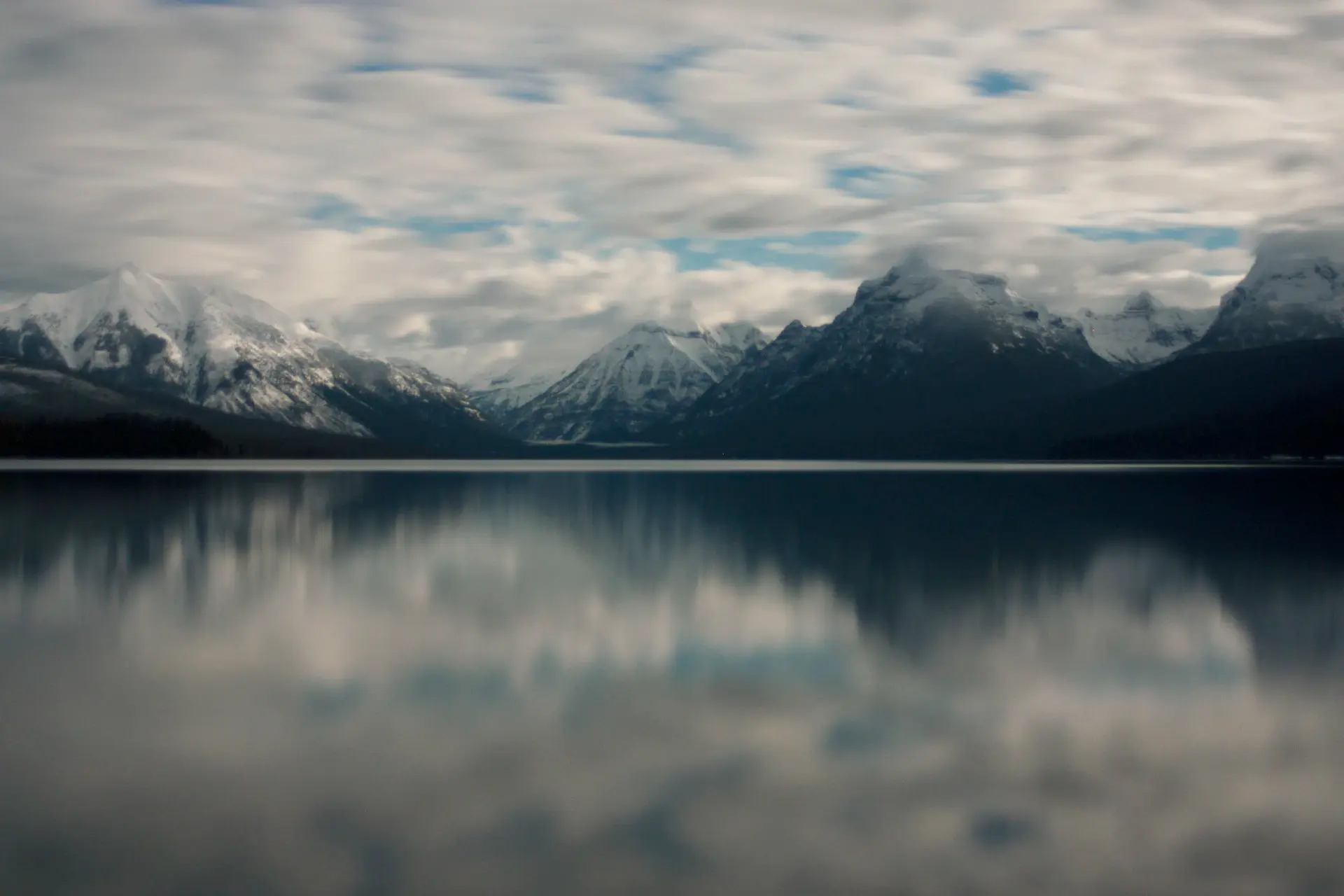 A still glacial lake mirroring jagged grey mountains