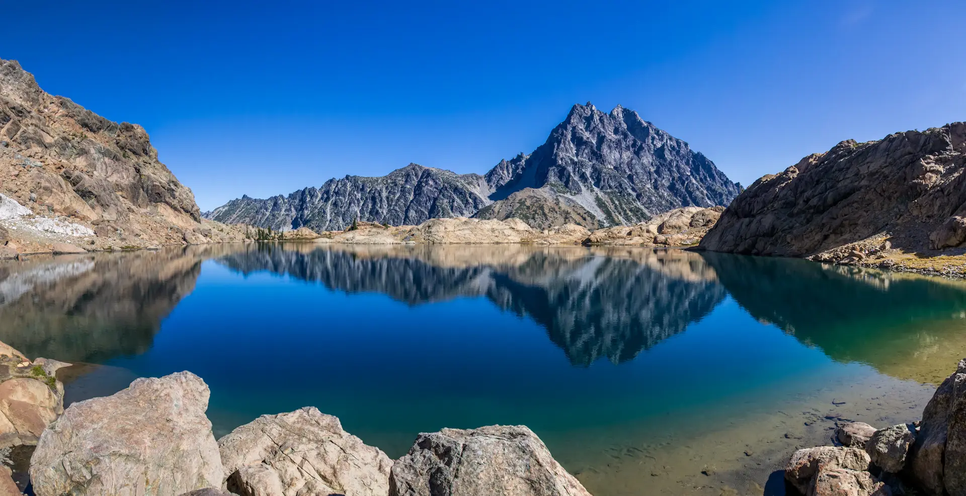 A mirror-still alpine lake reflecting jagged peaks