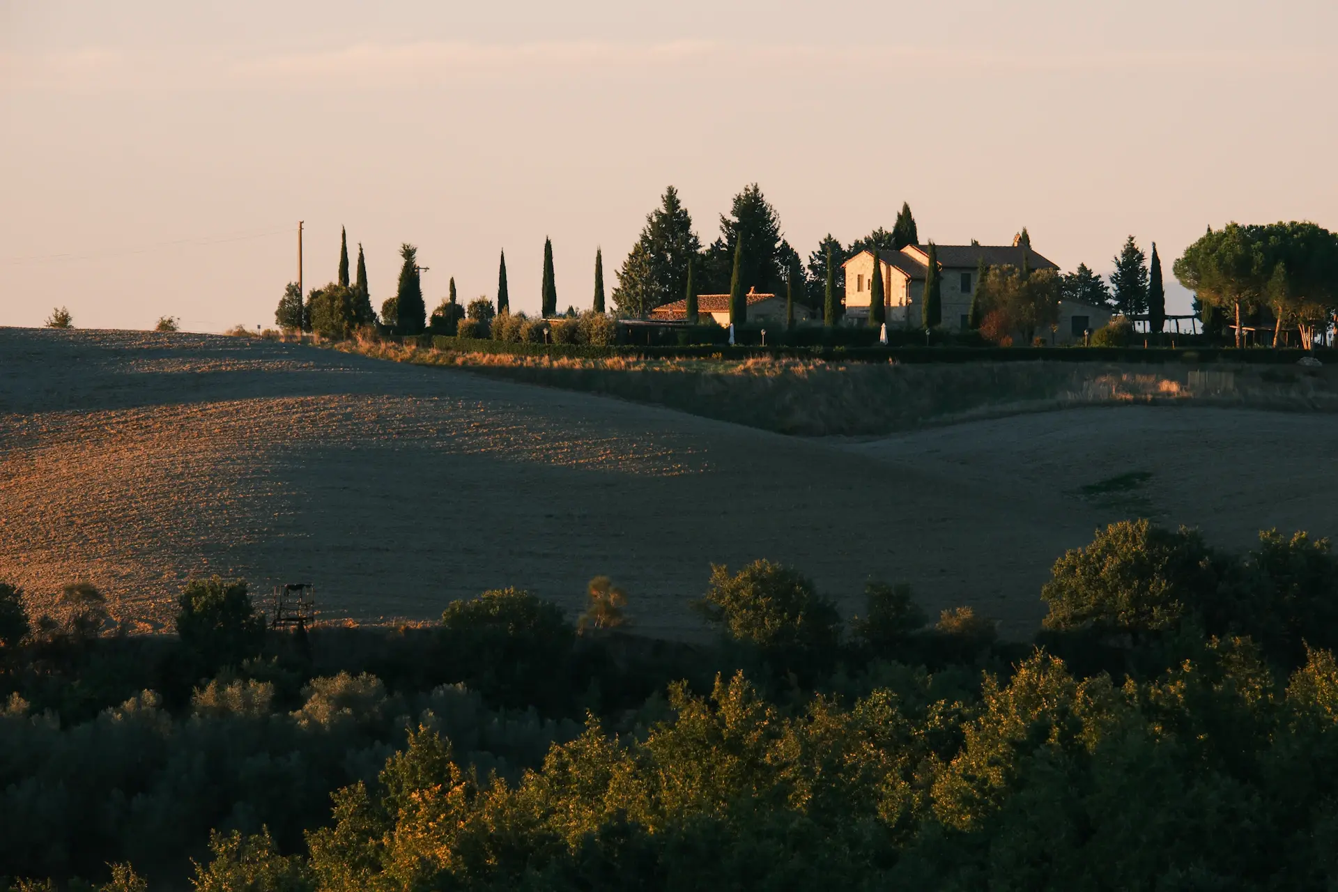 A luxury motorcar parked before a private Tuscan villa at dusk