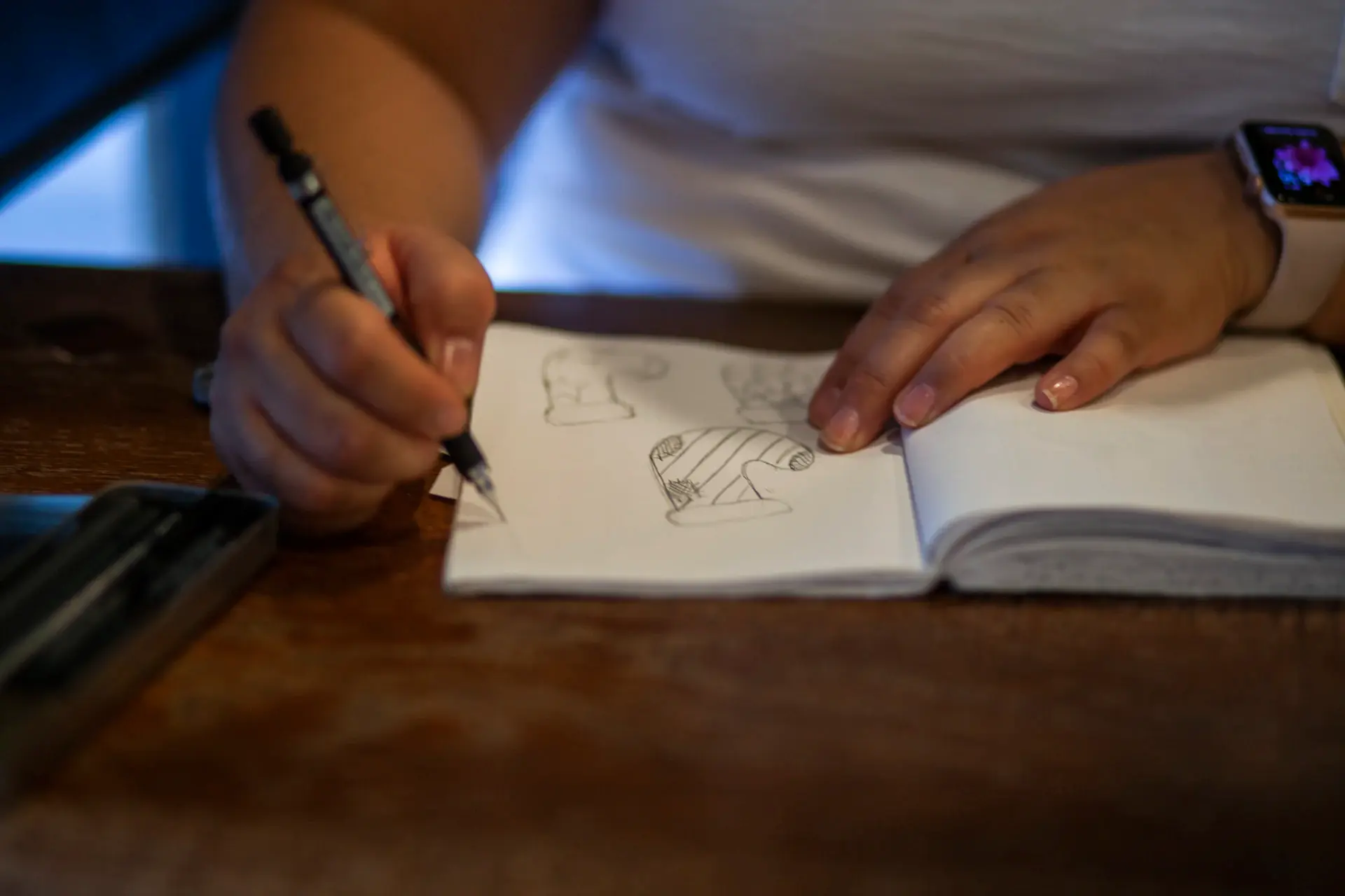 Hands sketching layout ideas in a paper notebook