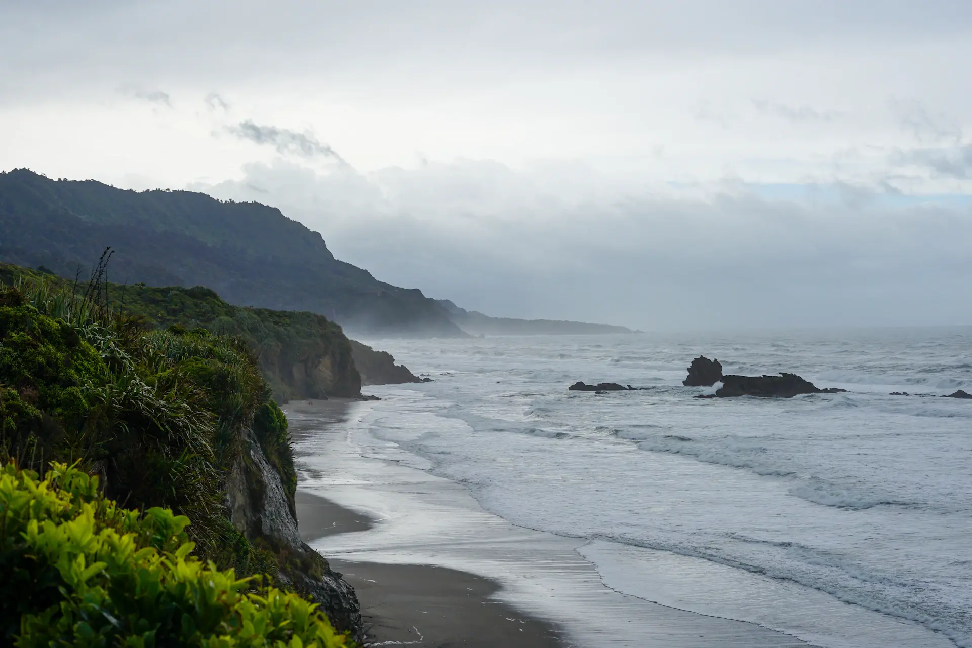 Waves breaking against dark coastal cliffs at dusk