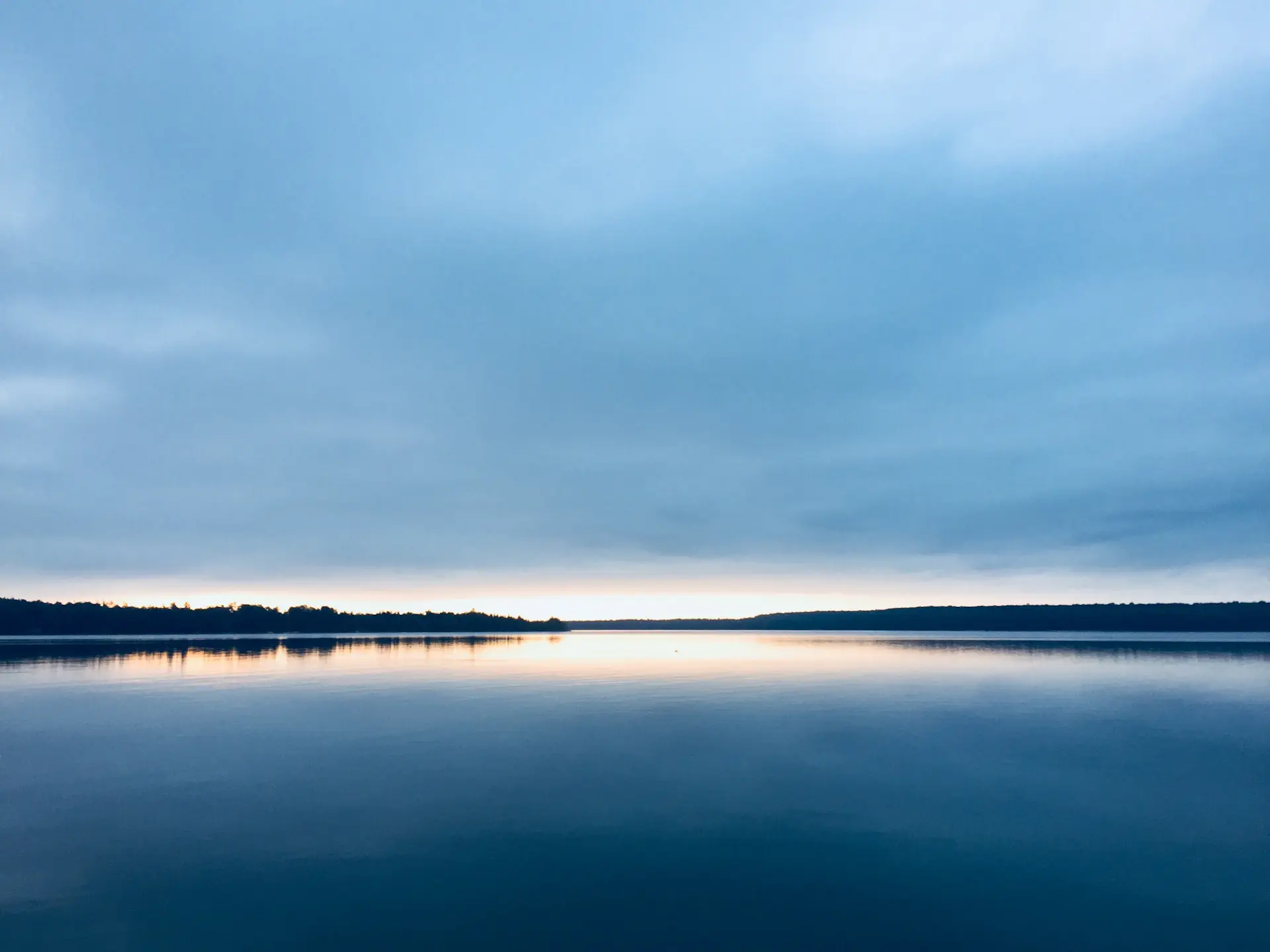 Cinematic wide lake at dusk with low mist over still water