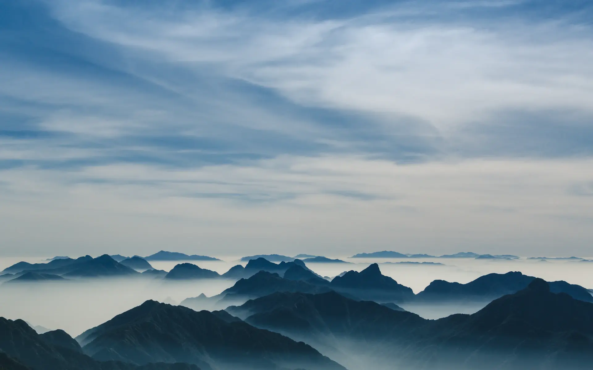 Snow-dusted alpine ridgeline above a sea of cloud