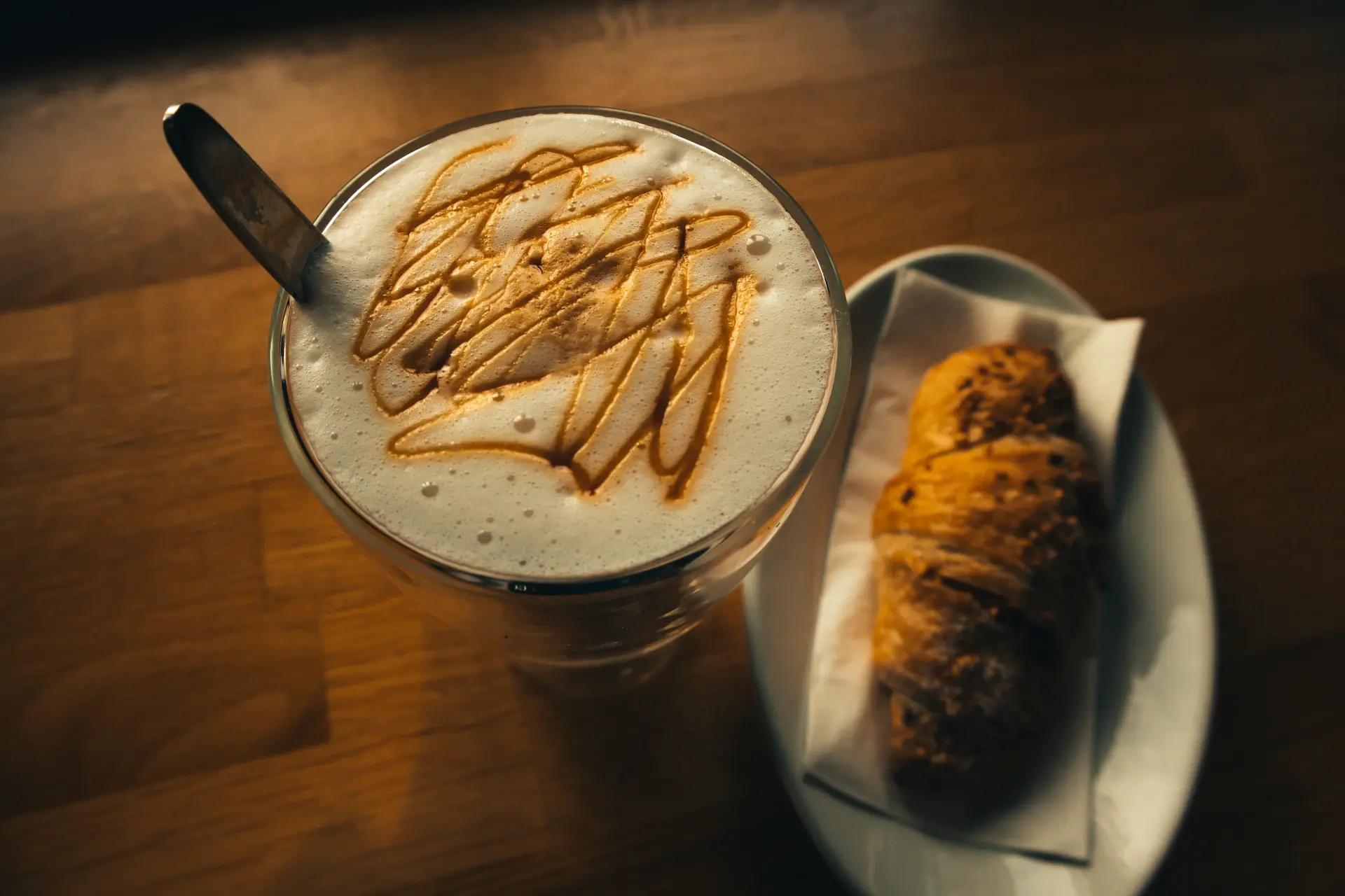 Honey latte beside an almond croissant