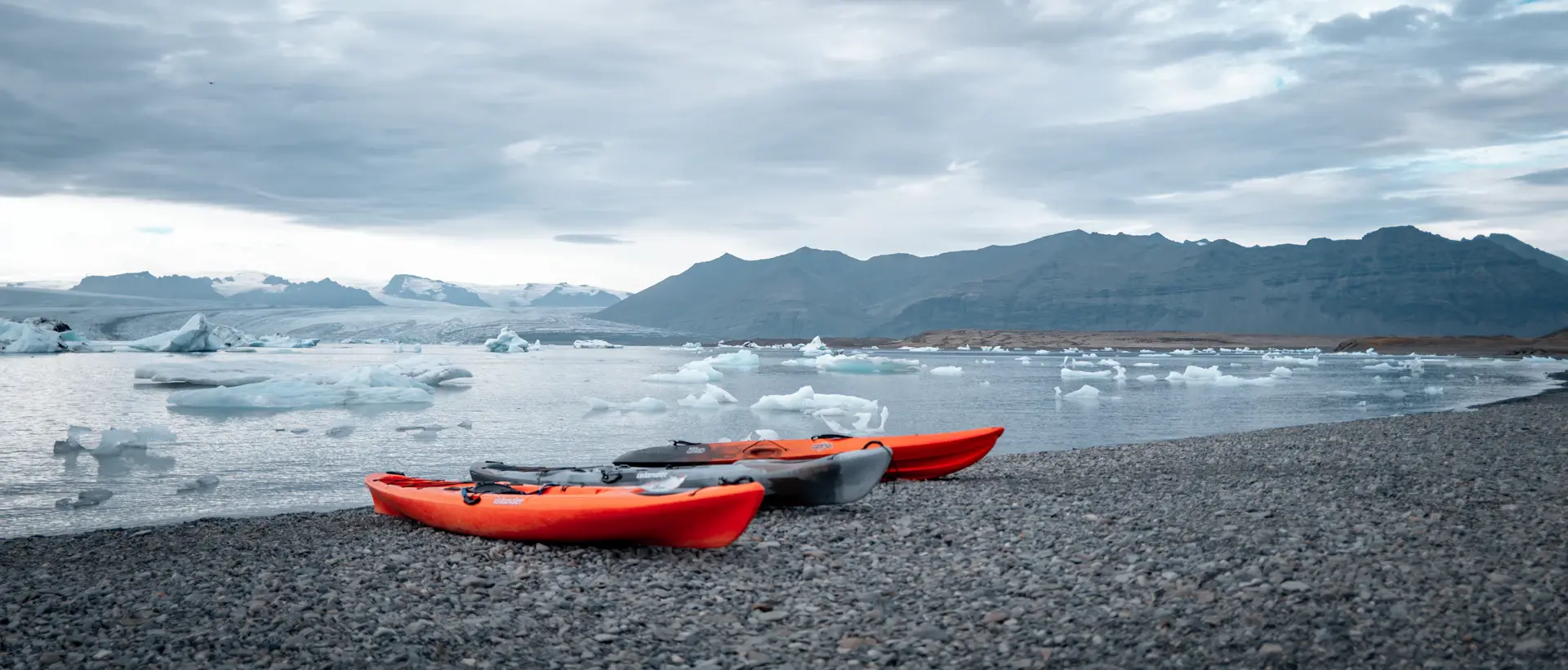 Kayakers paddling past sculptural blue icebergs in still water