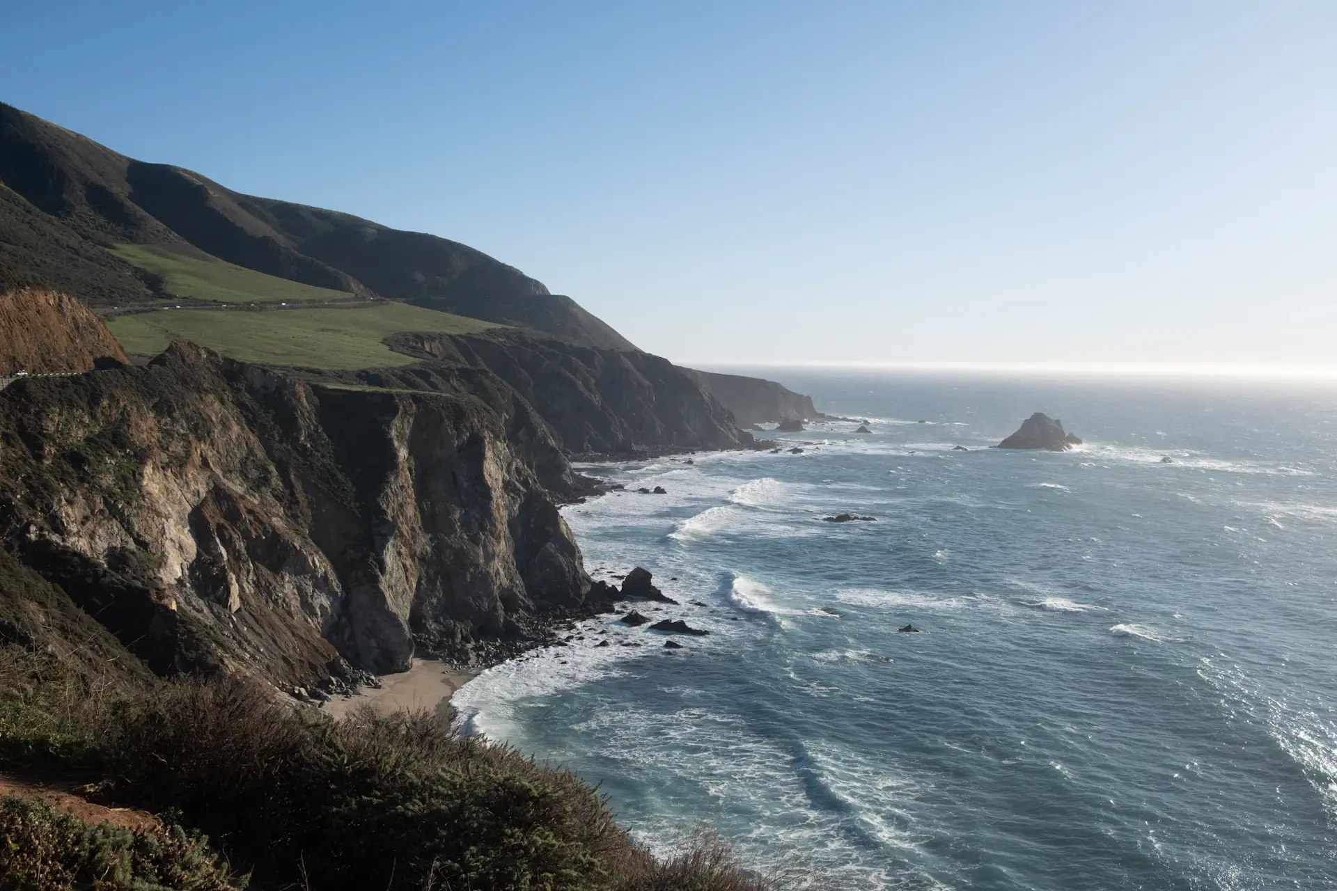 Surf wrapping around rugged cliffs at dusk