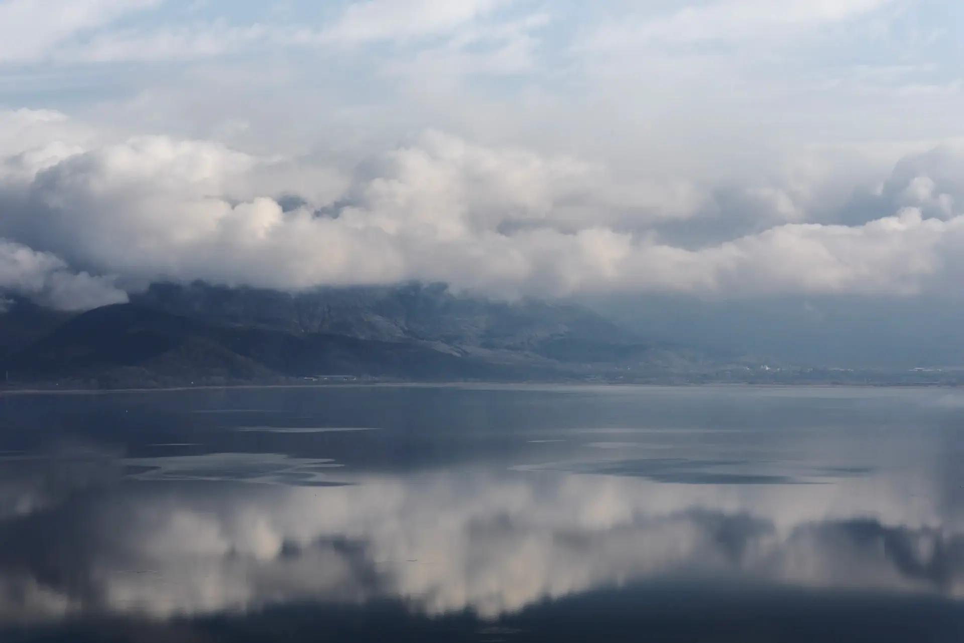 Clouds clearing over a moody lake surface