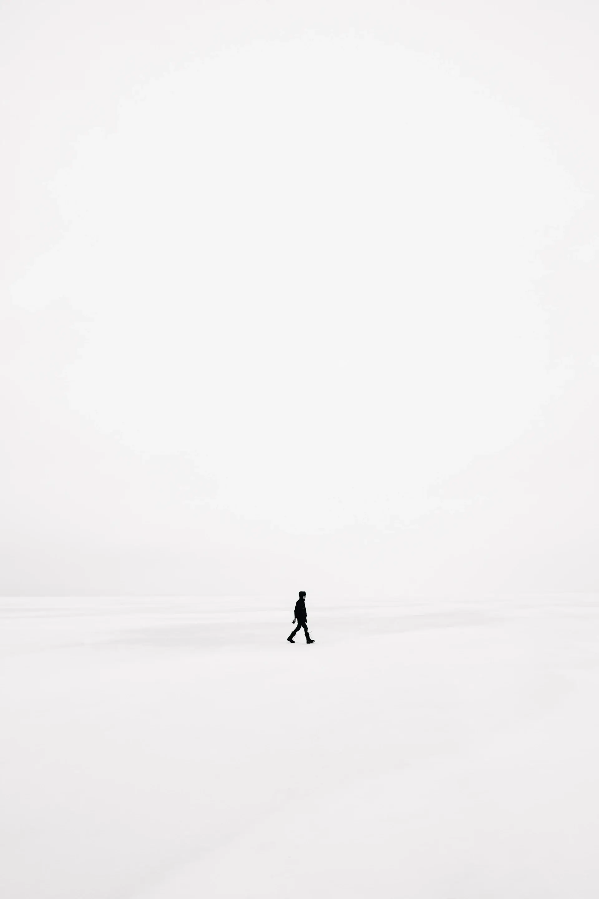 A solitary figure crossing a vast pale dune