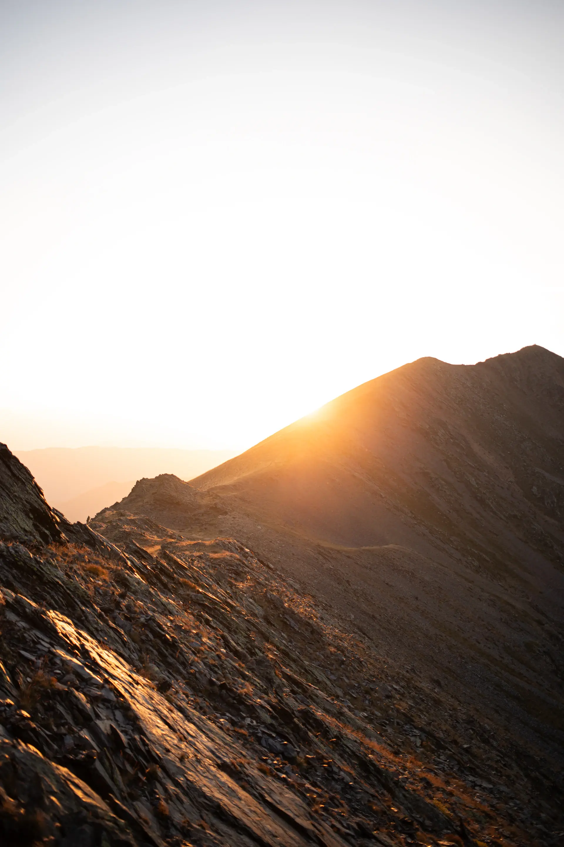 Pale gold light touching a distant misty ridge
