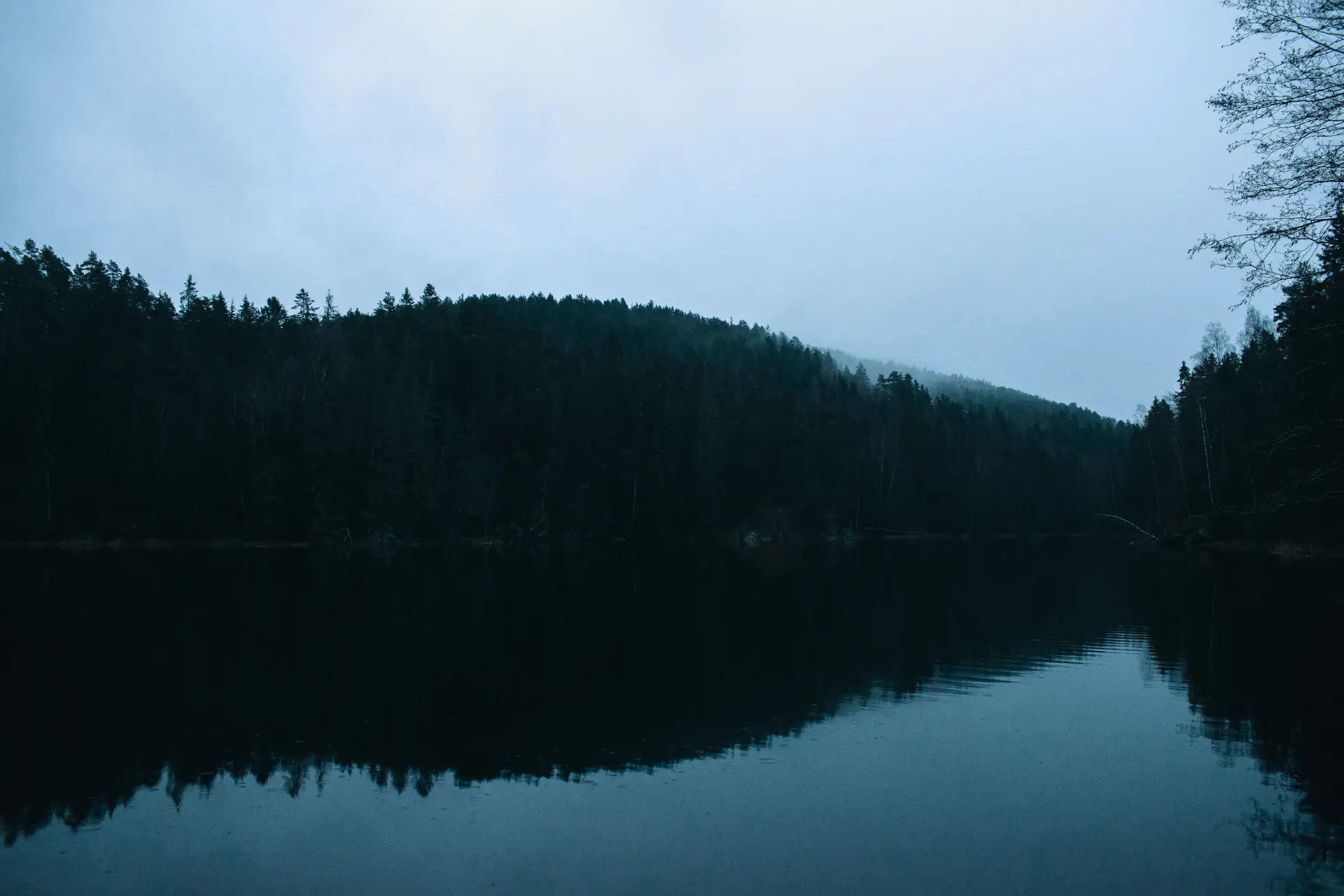 Dark glassy lake under a thin band of pre-dawn light