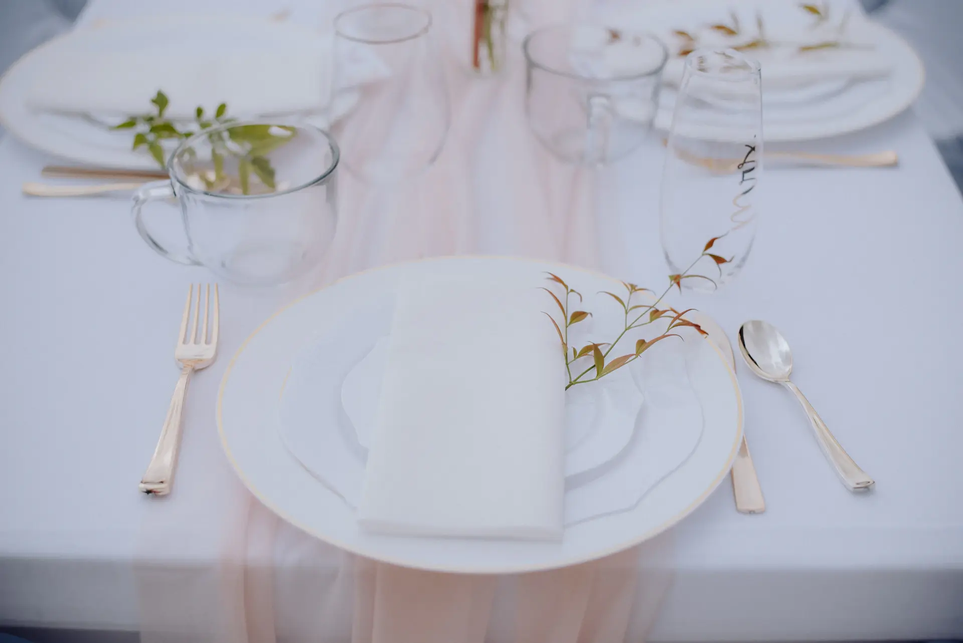 Gold-rimmed glassware and place settings on a white cloth