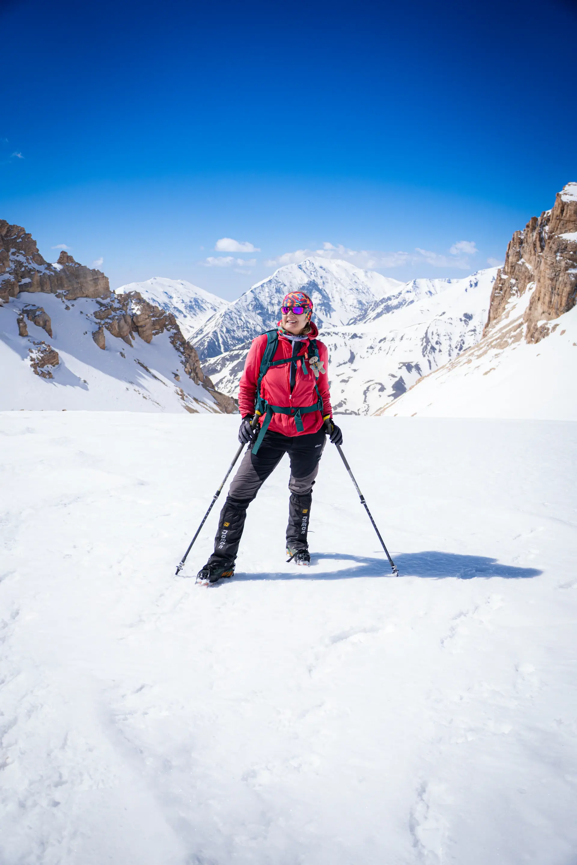 A lone climber on a high snowfield beneath a vast pale sky