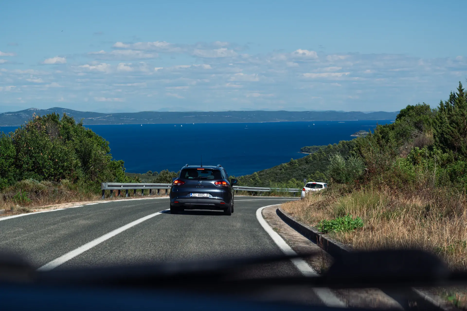 A 1950s grand touring motorcar on an open coastal road