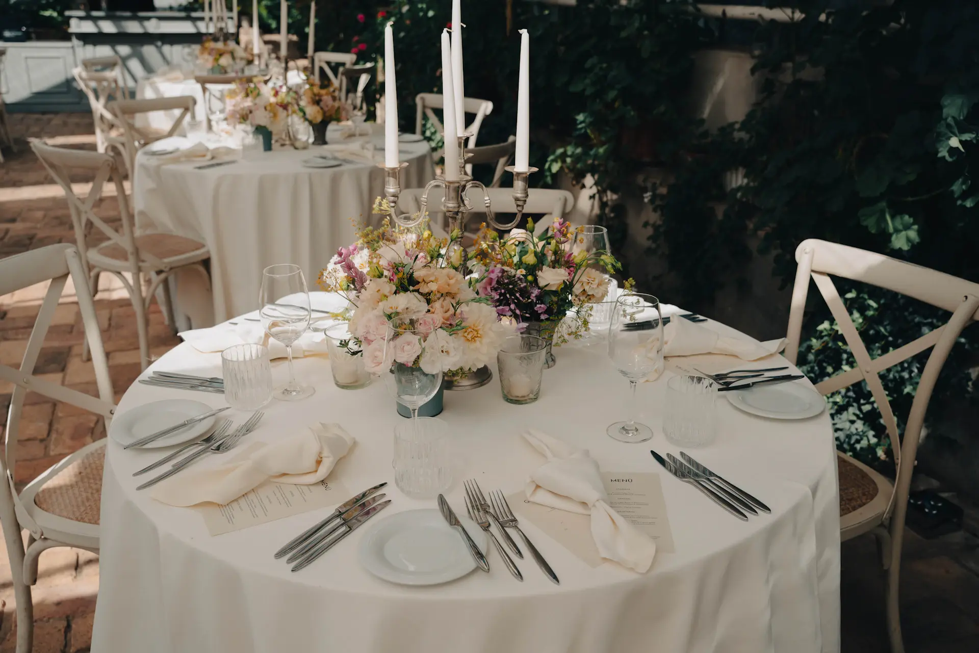 An elegantly styled wedding table setting with ivory linens, gold accents and fresh florals