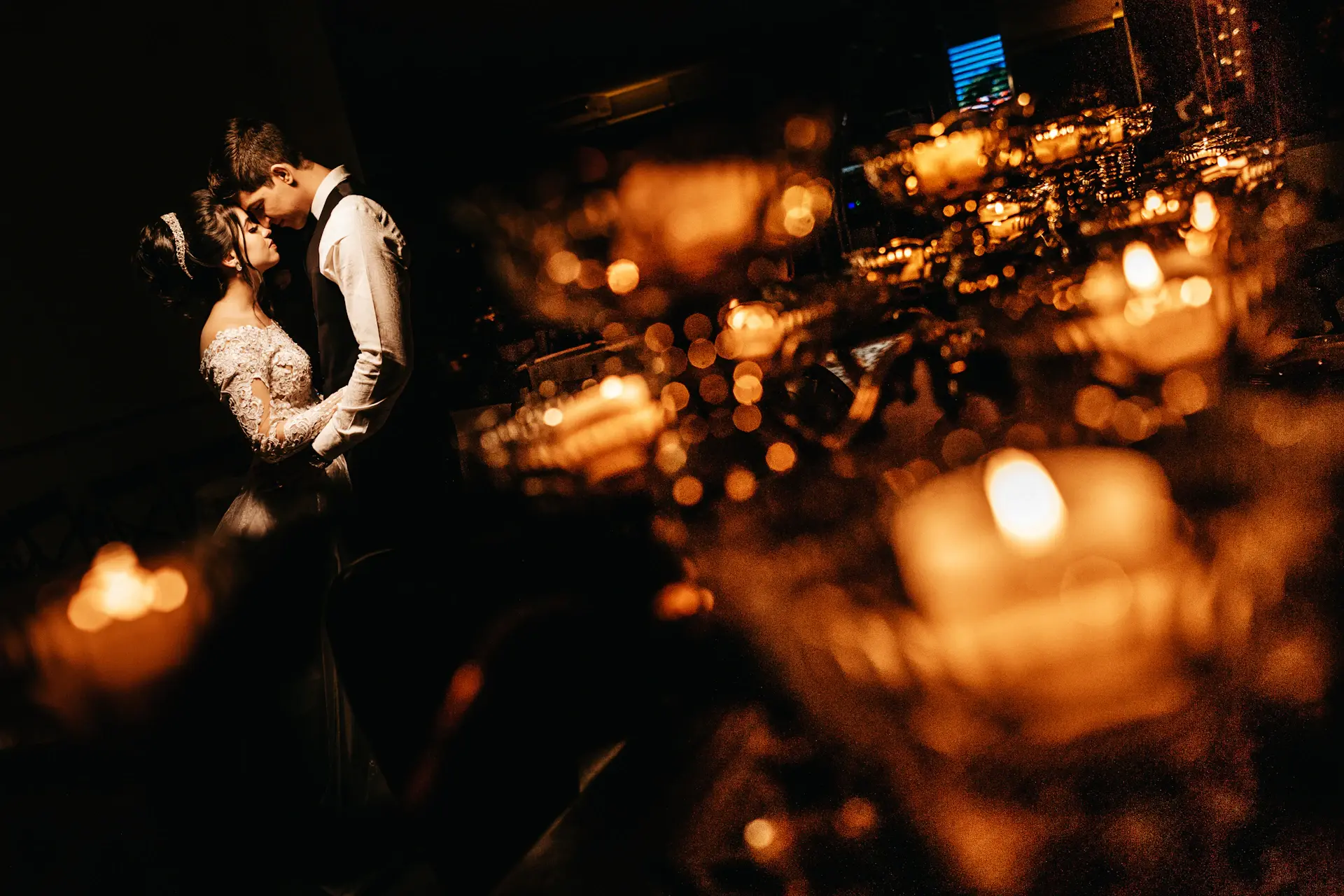 A bride and groom in a candlelit grand ballroom