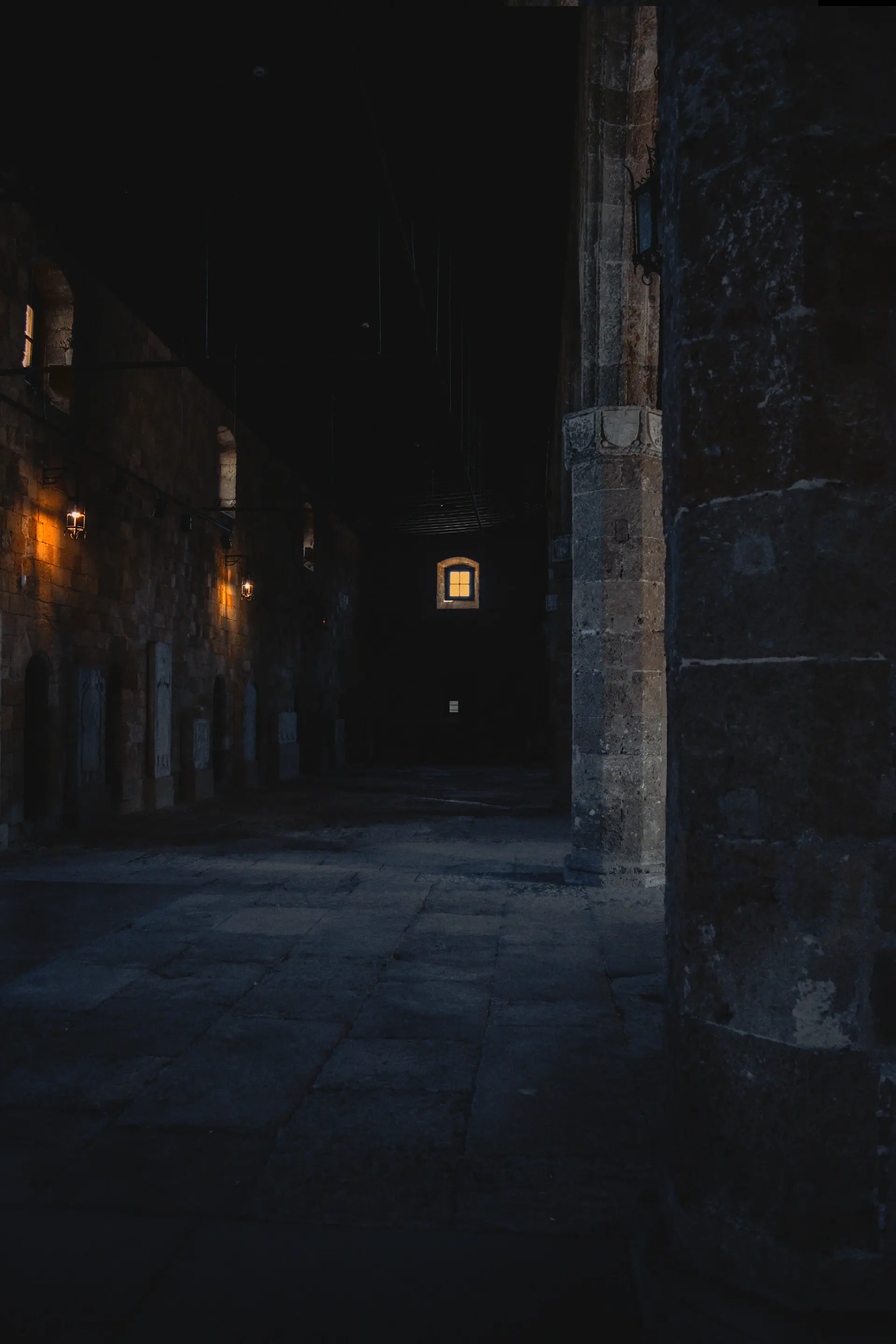 Lantern-lit stone alleyway in an ancient walled city at night