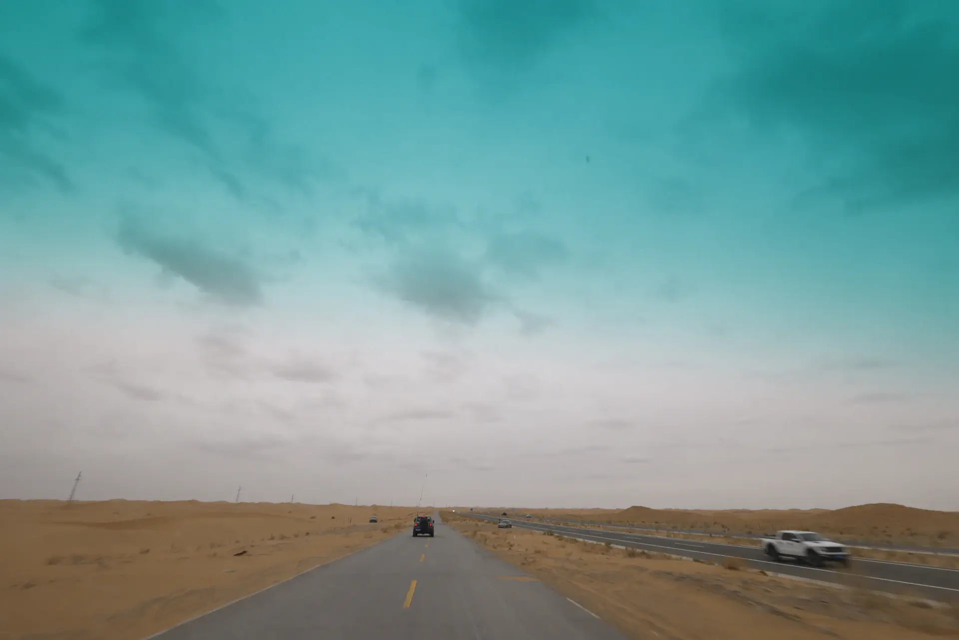 A luxury motorcar on an open desert highway at golden hour