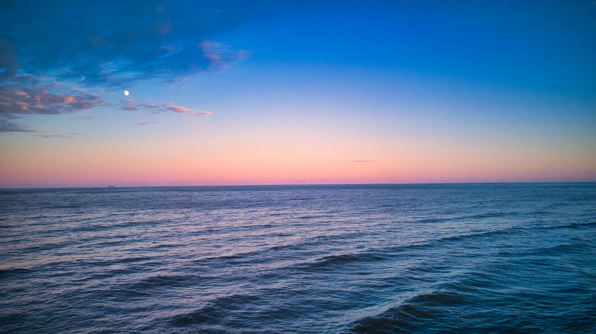 A distant horizon at dusk seen from the deck of a departing vessel