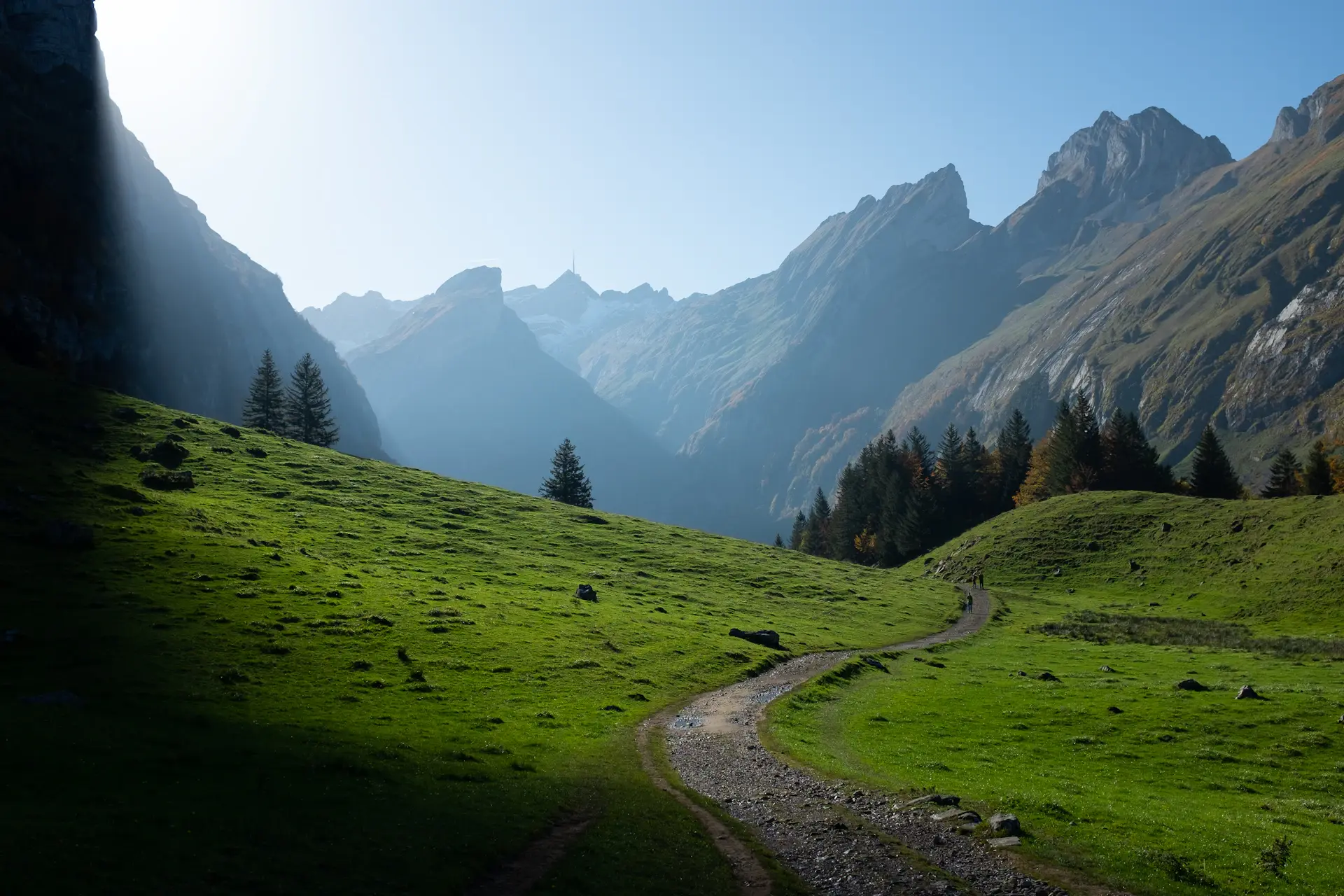 A traveller pausing on a misted mountain path at dawn