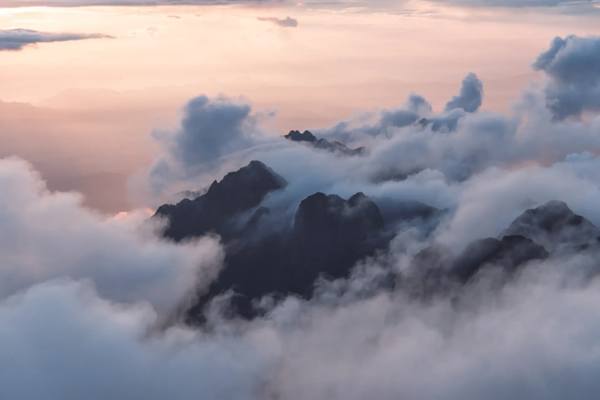 Alpine peaks glowing at sunrise above a cloud inversion