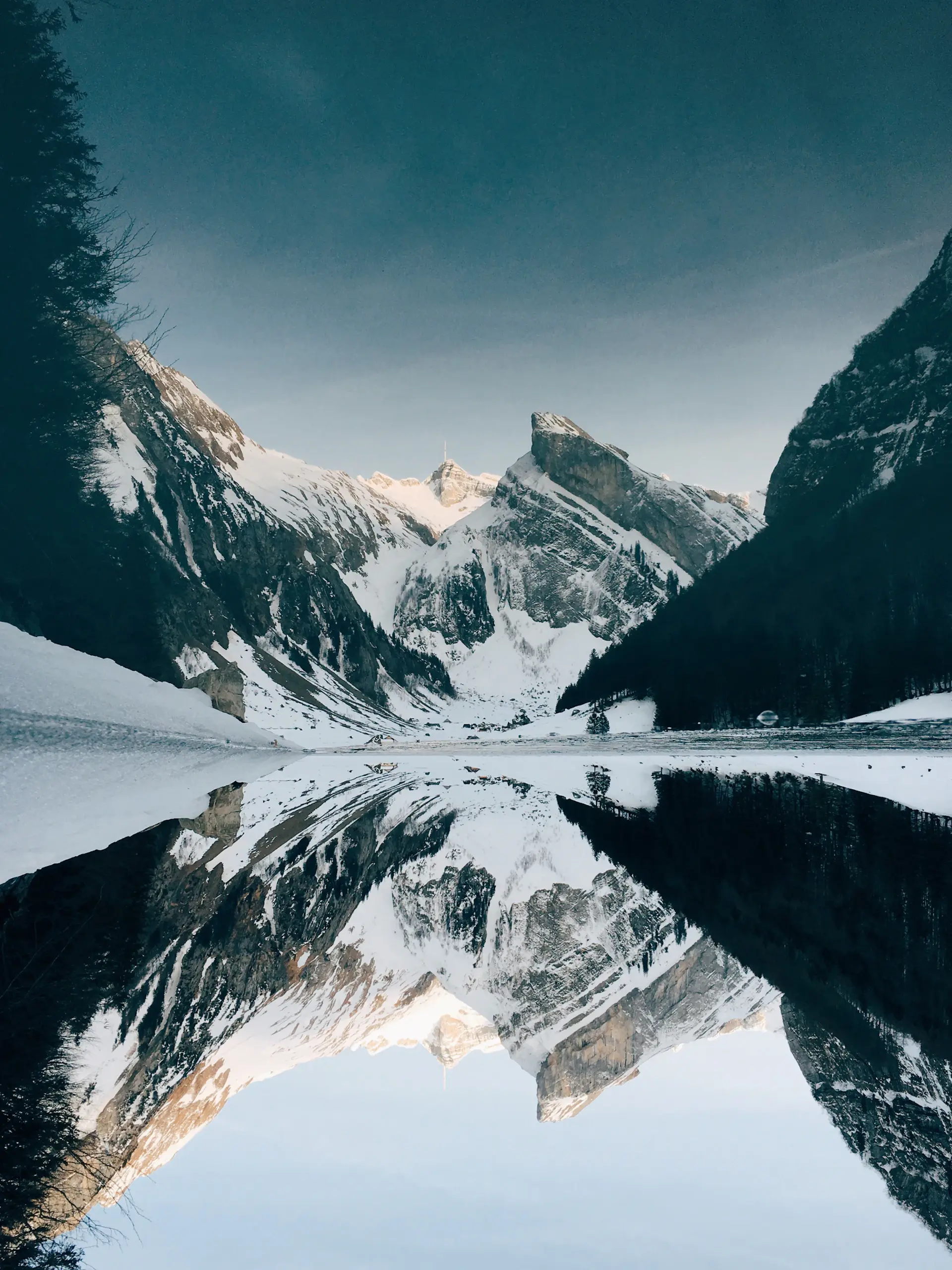 A still alpine lake mirroring snow-capped peaks