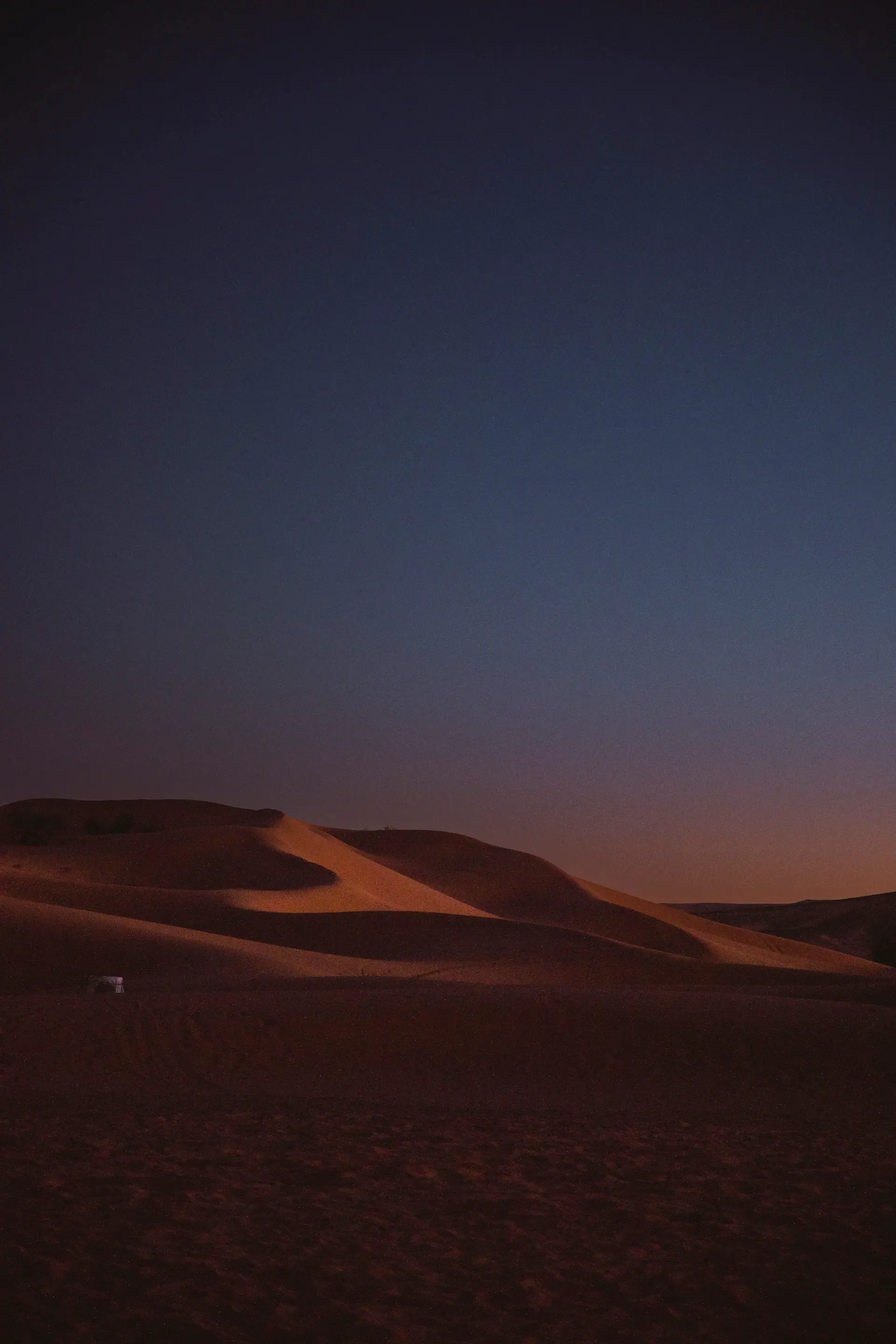Solitary camp beneath dunes at dusk in the Empty Quarter
