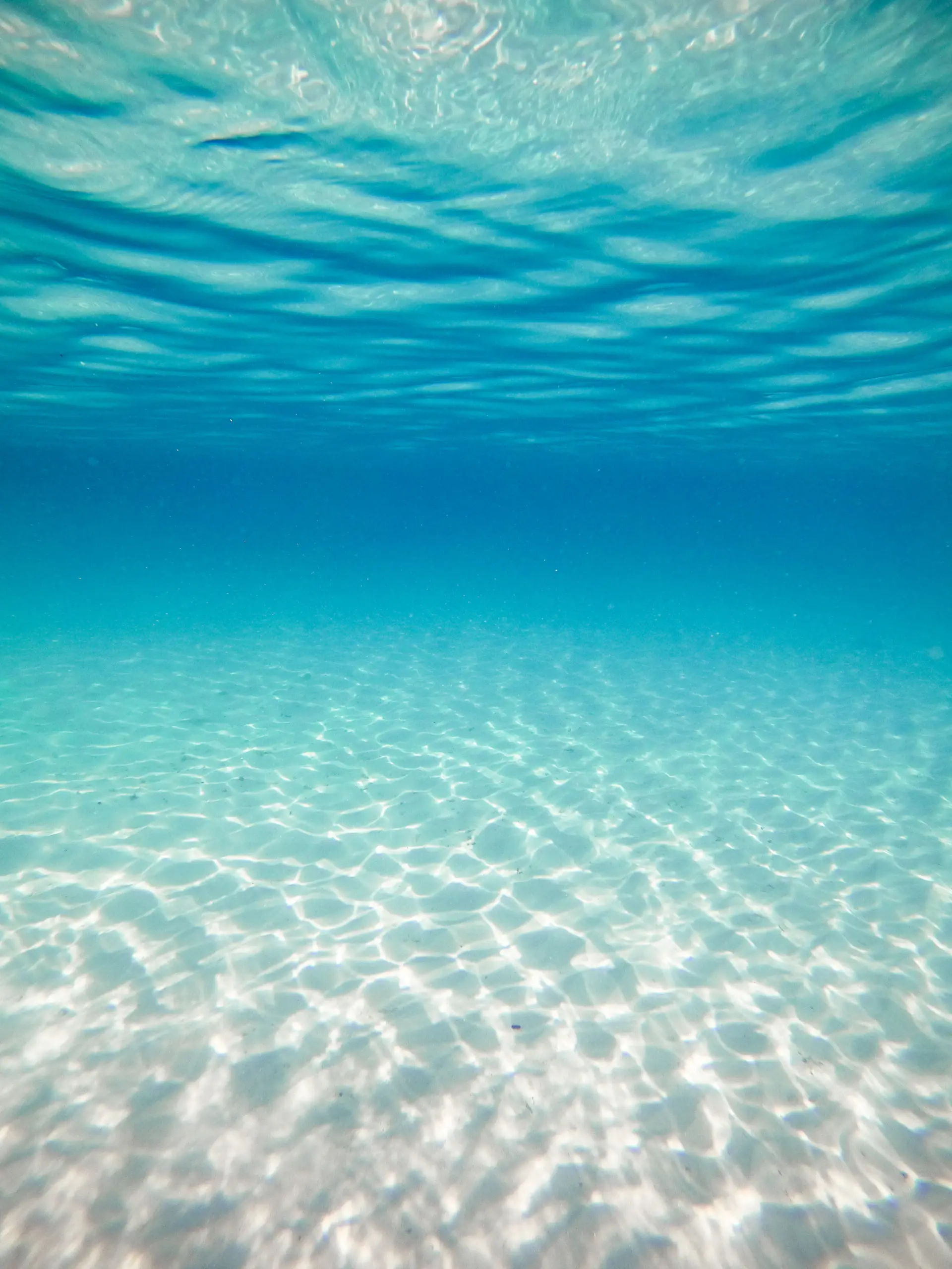 Shafts of light sinking through clear blue water