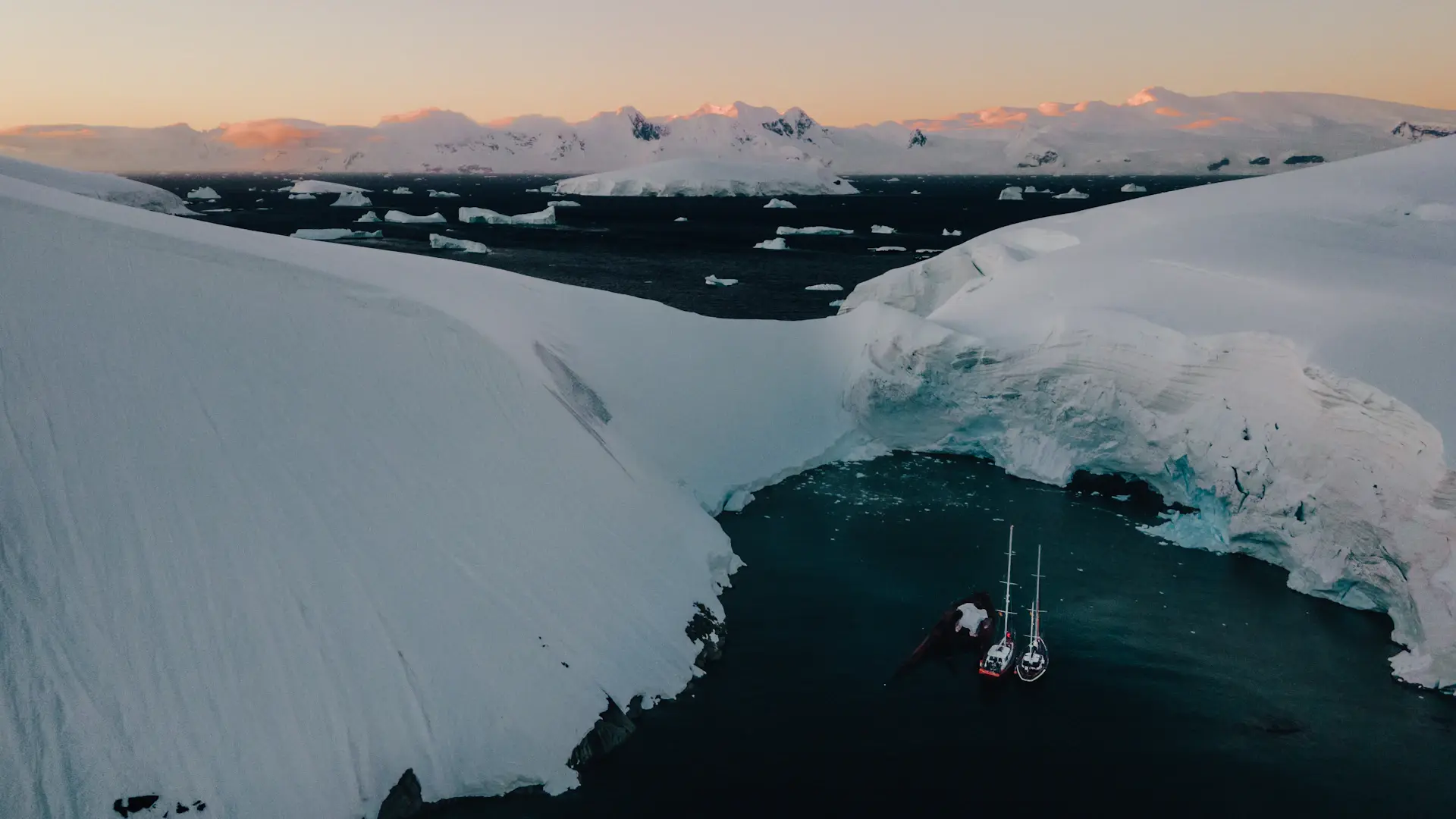 An expedition ship dwarfed by towering Antarctic ice