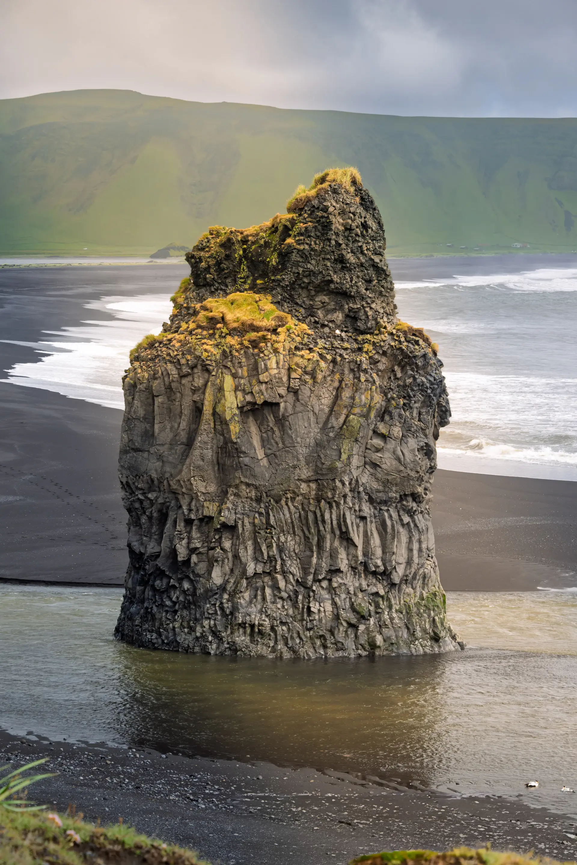 A wide waterfall thundering over a black basalt cliff