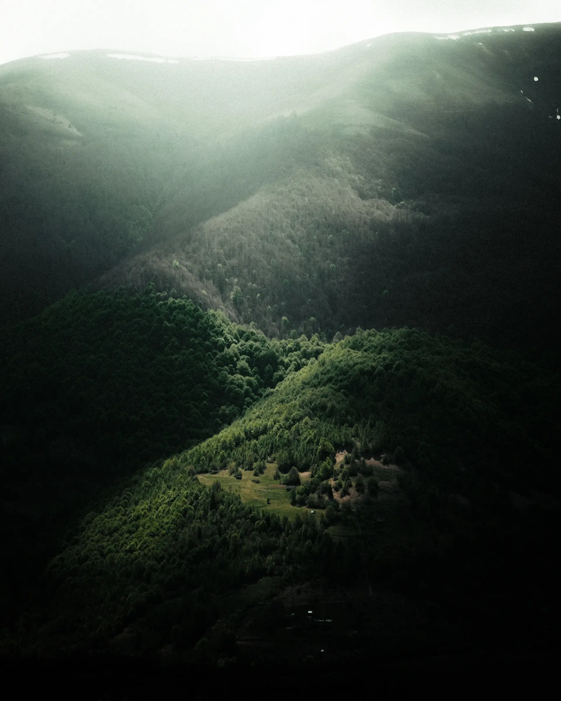Fog pooling in a green valley between dark ridgelines