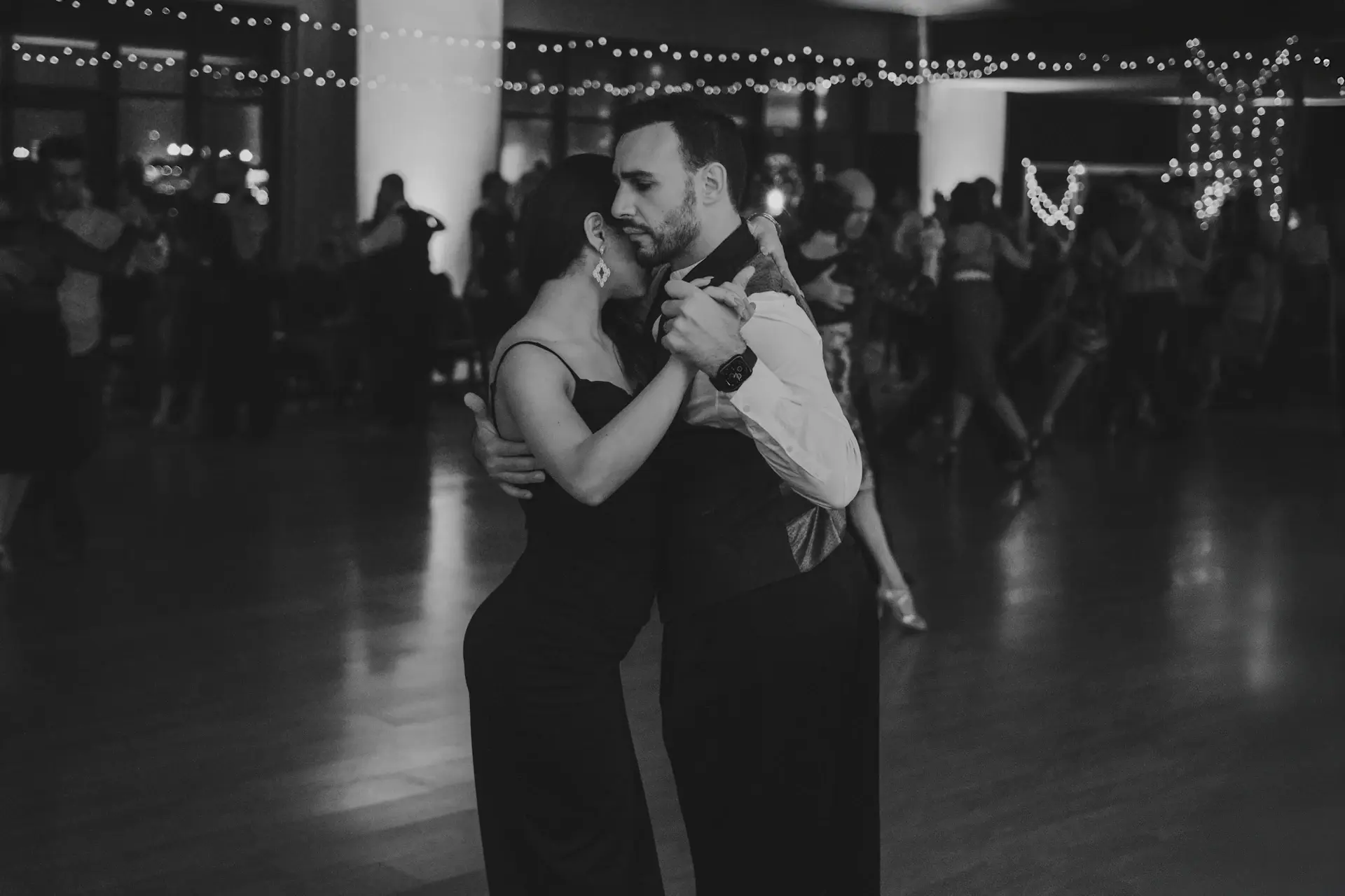 A couple sharing their first dance beneath chandeliers in the candlelit ballroom