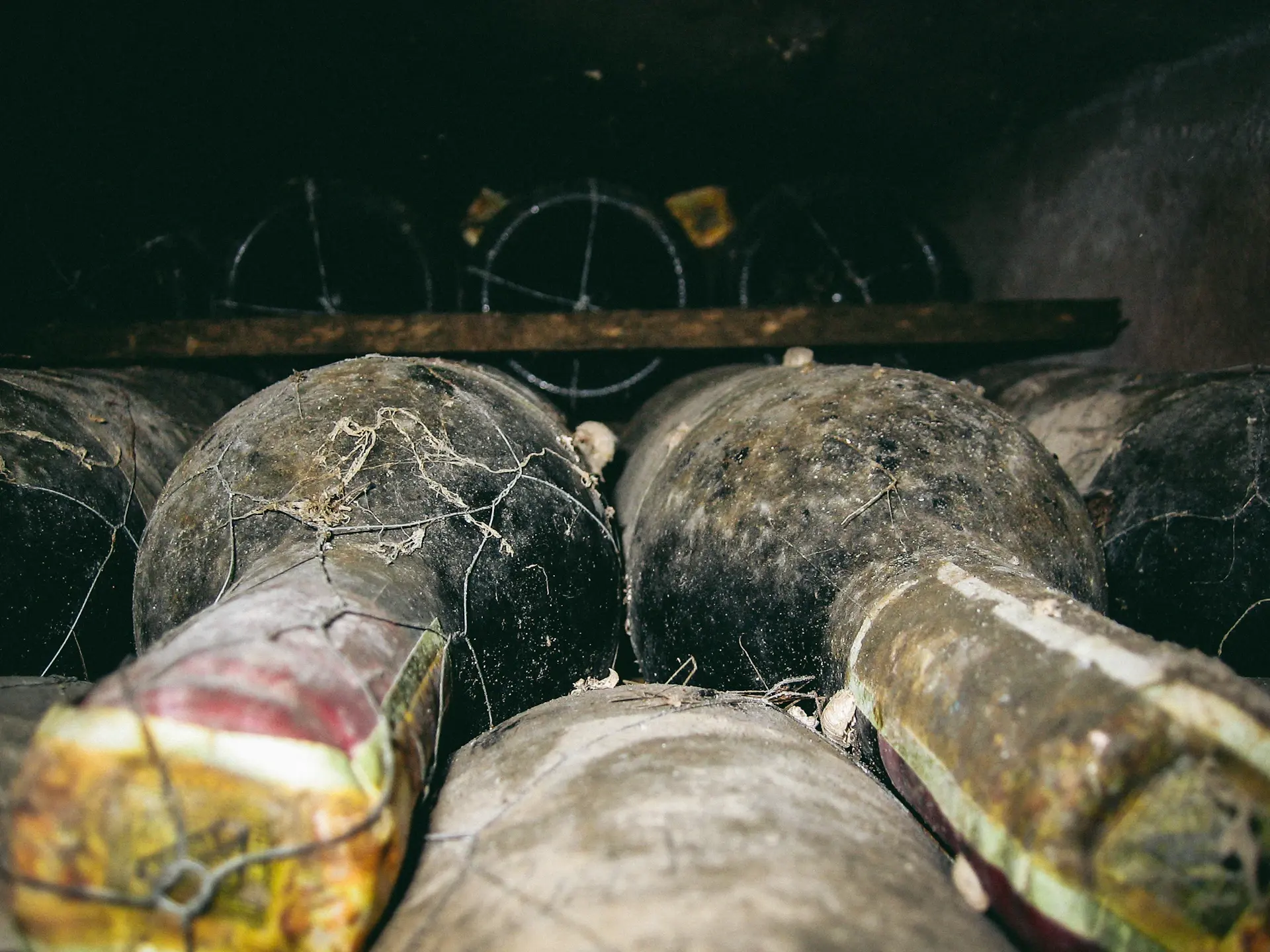 Dust-veiled bottles resting on aged oak racks in a candlelit private cellar