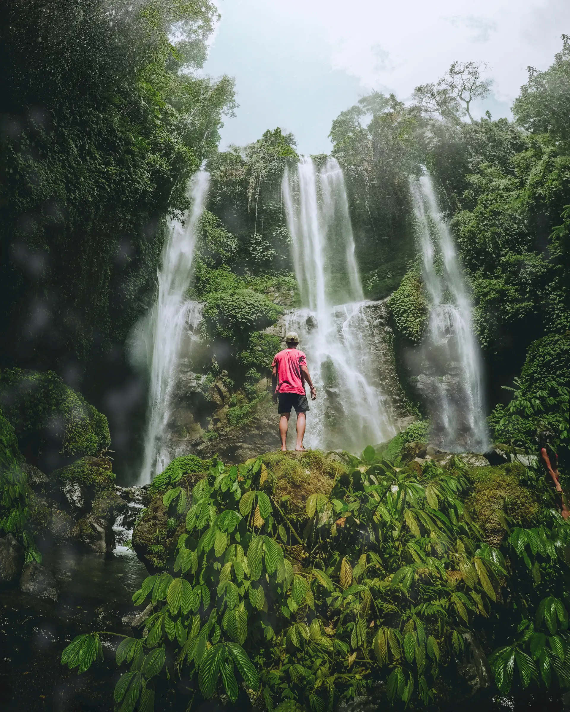 A photographer standing near the base of a thundering waterfall