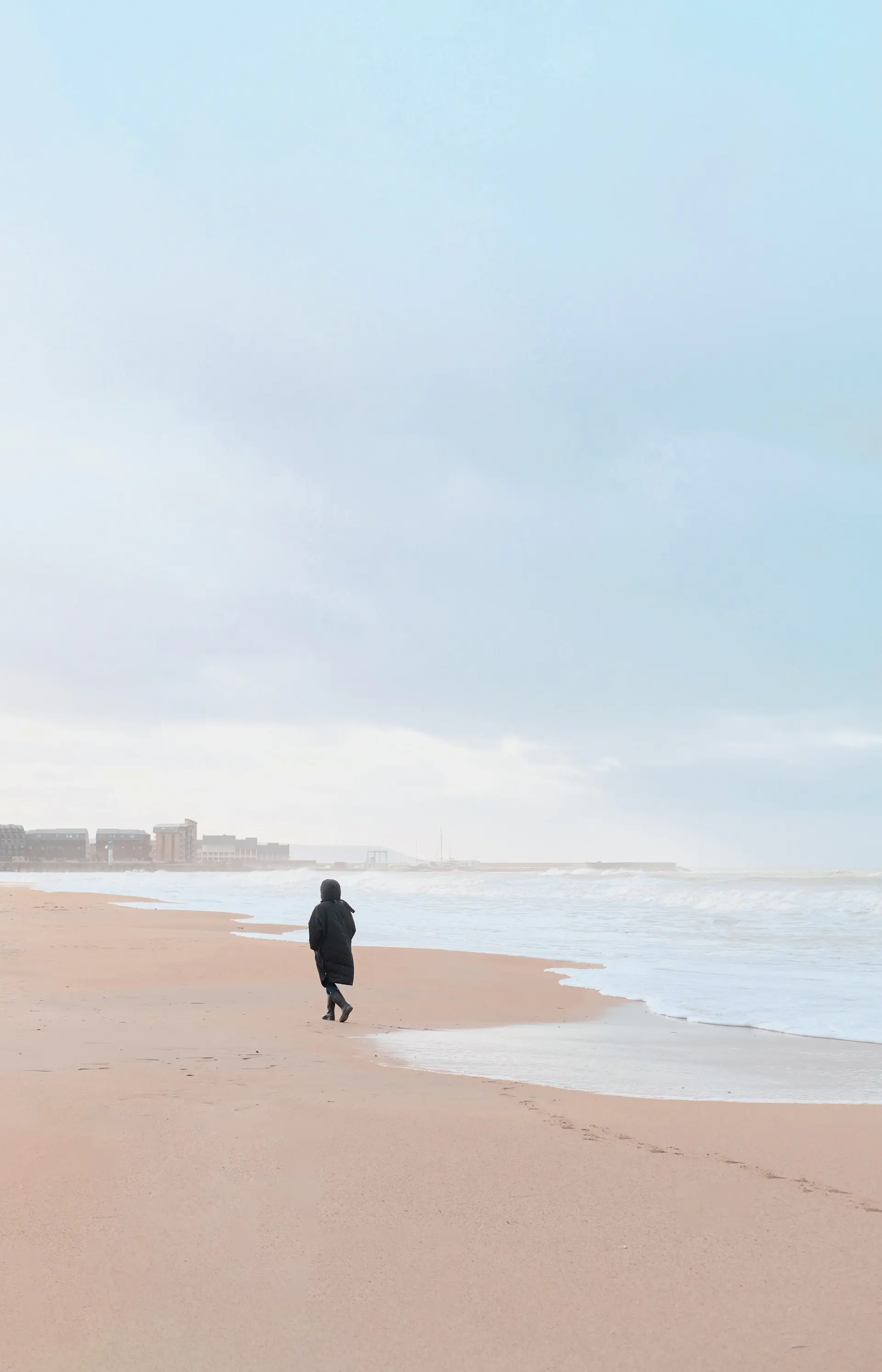 Lone figure walking a wide deserted winter beach