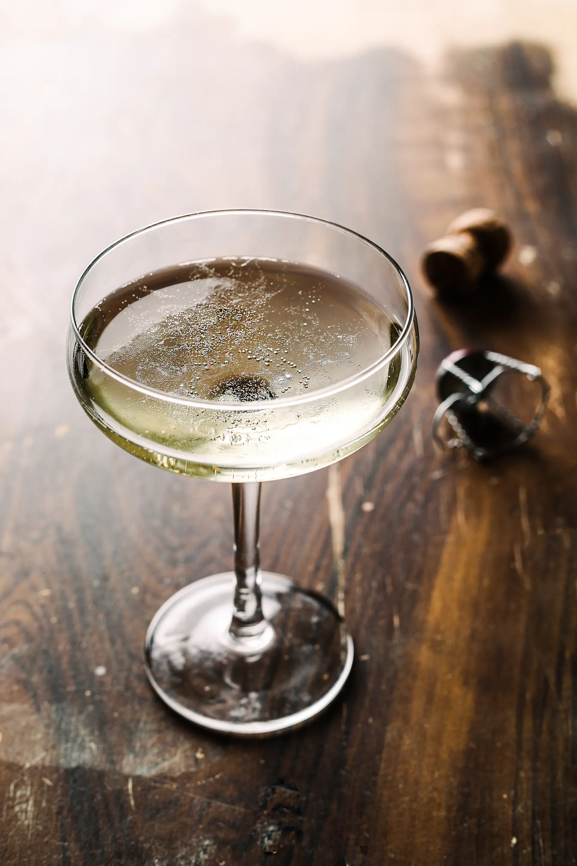 A coupe of vintage champagne with rising bubbles in golden light