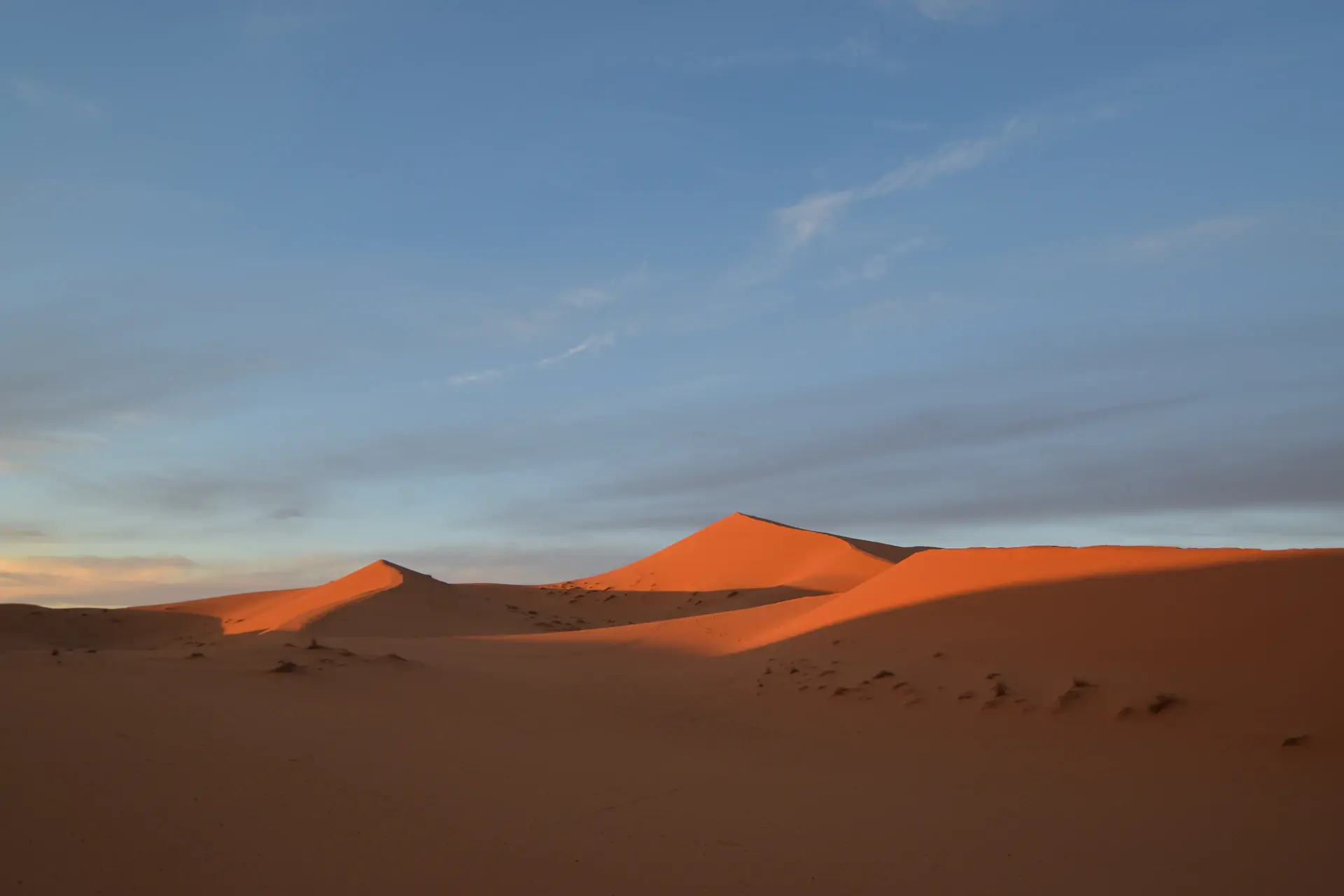An elegant private dinner table set among Saharan sand dunes at dusk