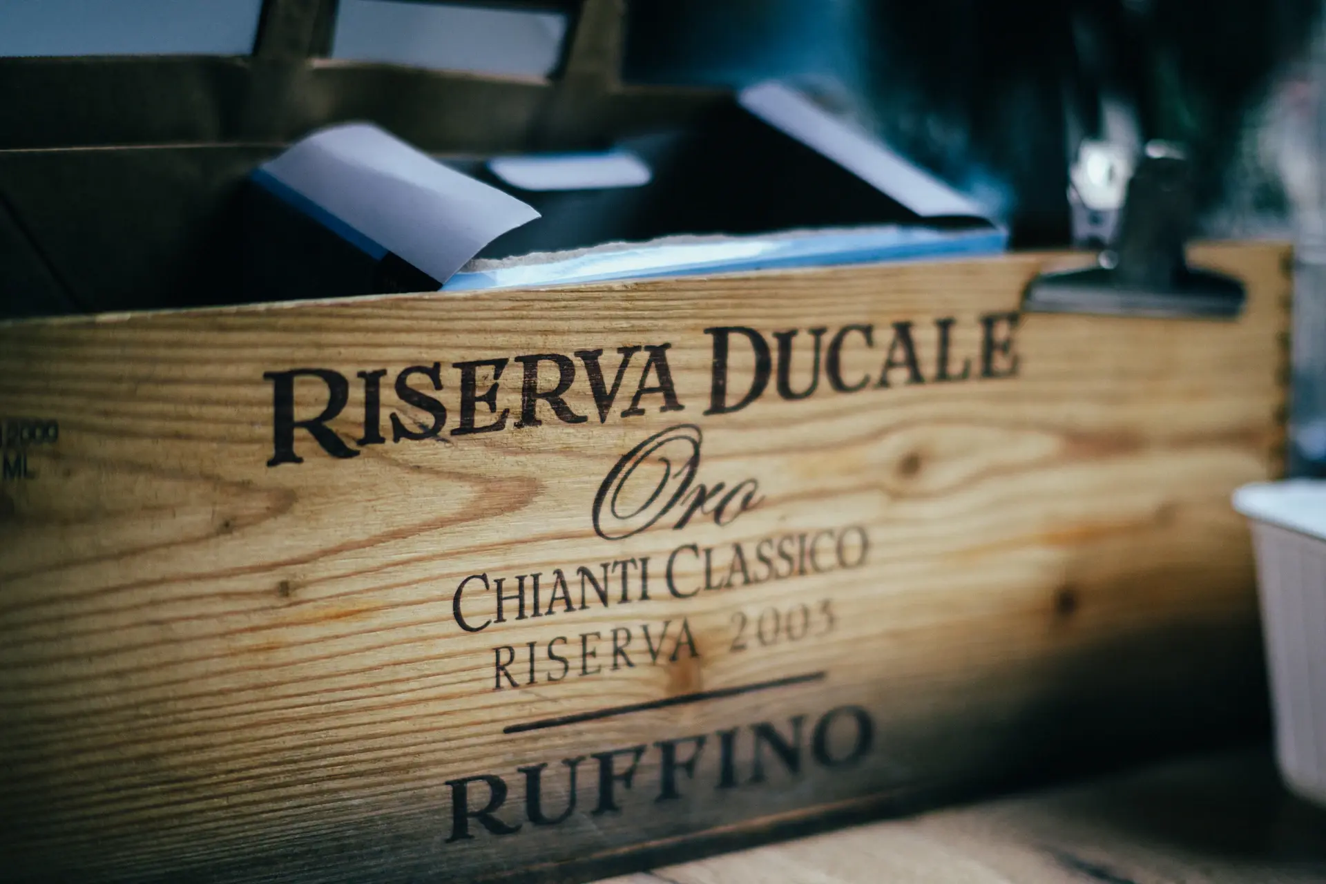 A gloved specialist carefully placing a wrapped bottle into an insured wooden crate