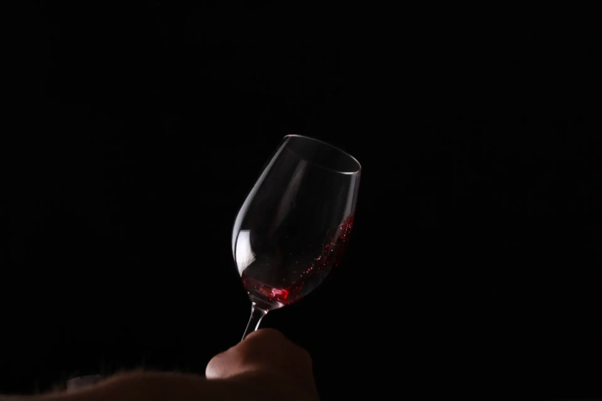 A taster nosing a glass of amber spirit in soft light