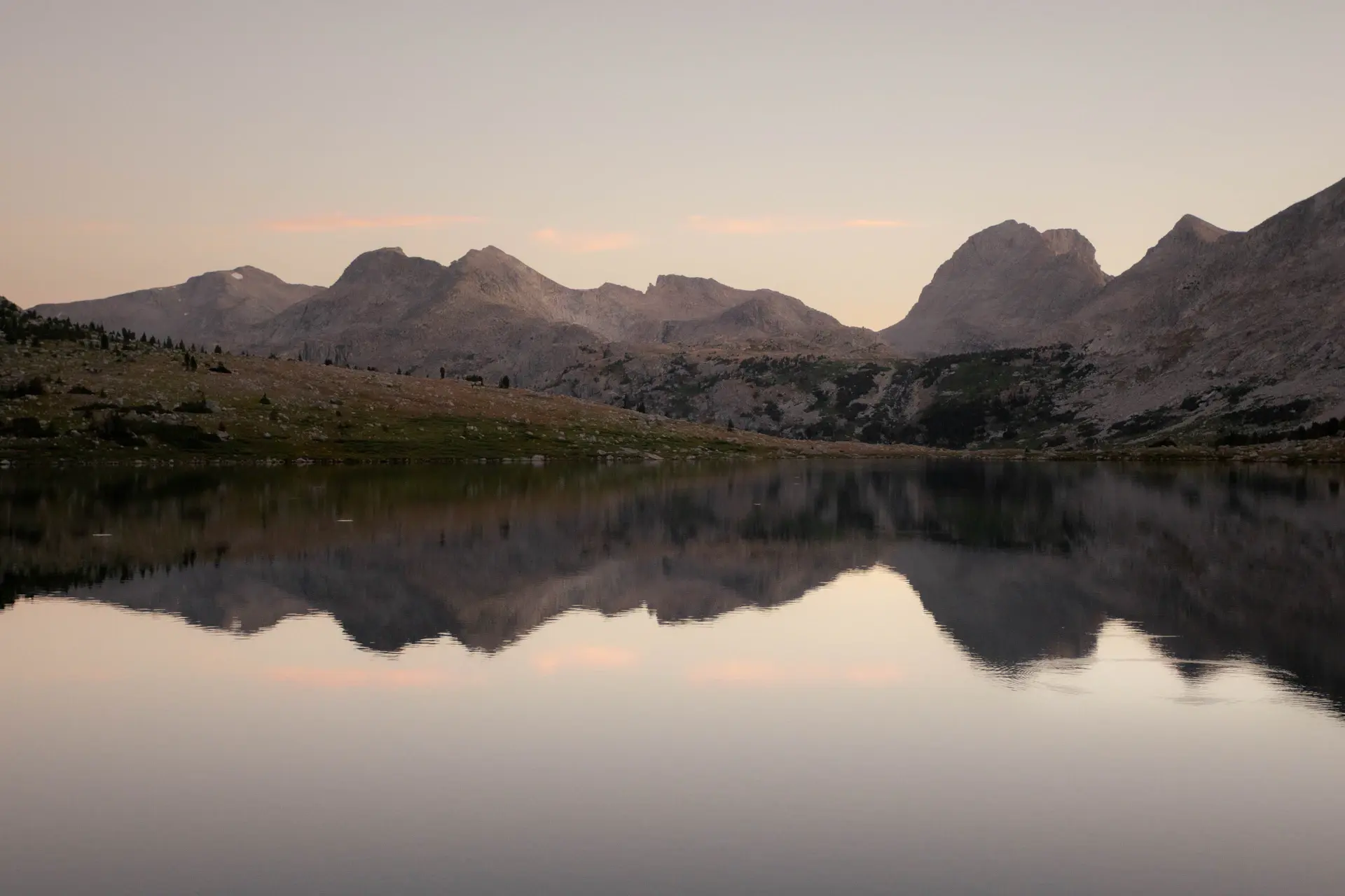 A glassy alpine lake mirroring mountains at first light