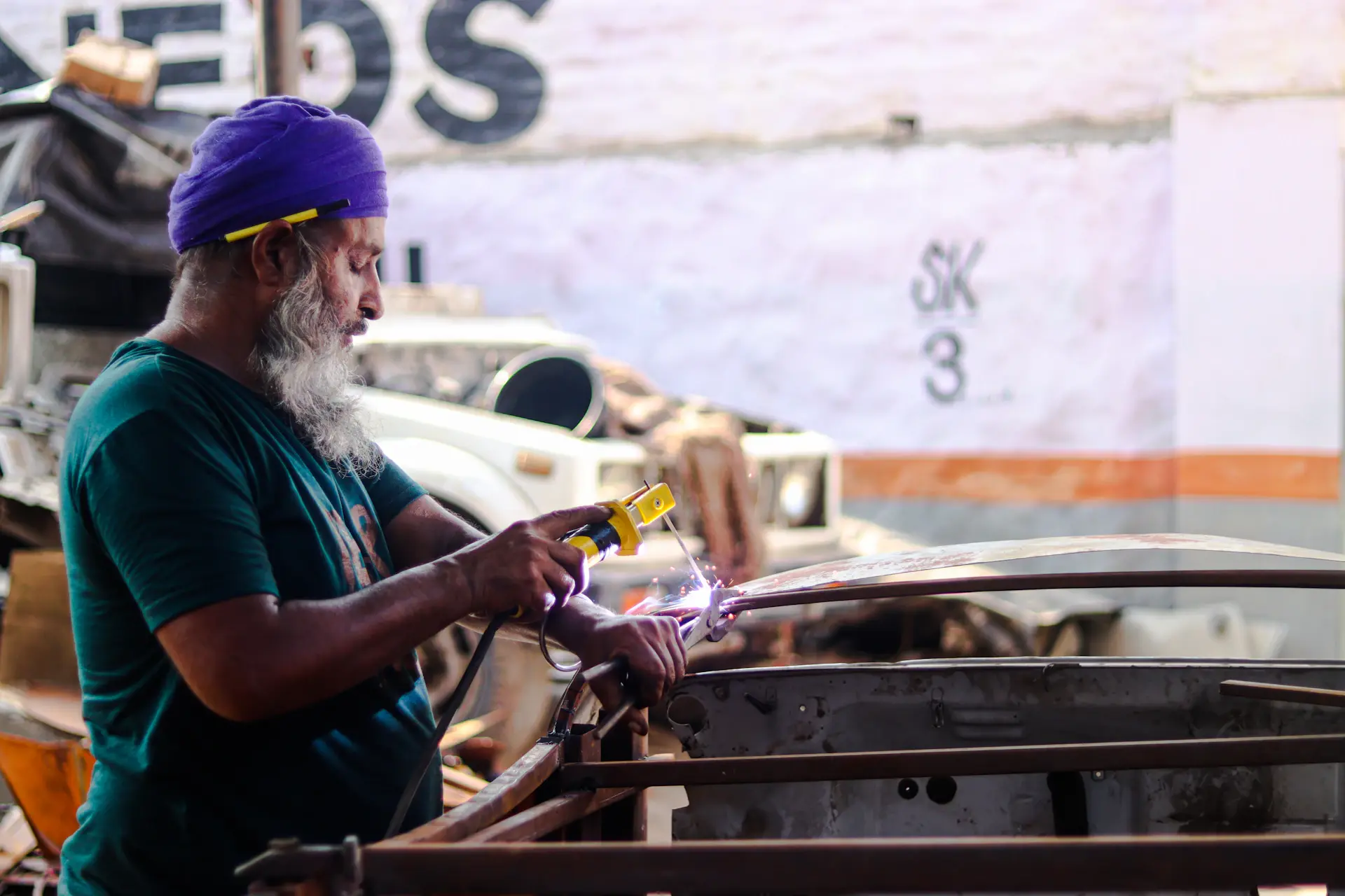 Craftsman hand-working a metal body panel of a luxury car