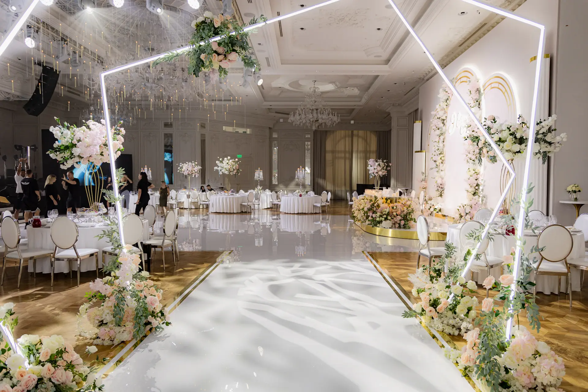 The ceremony arch of white blooms framed by gilded columns