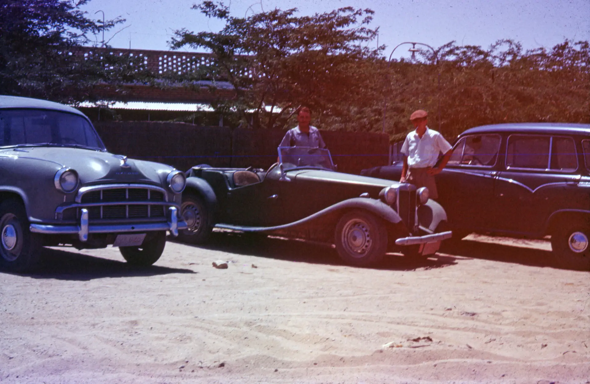 Early clients beside a grand touring motorcar
