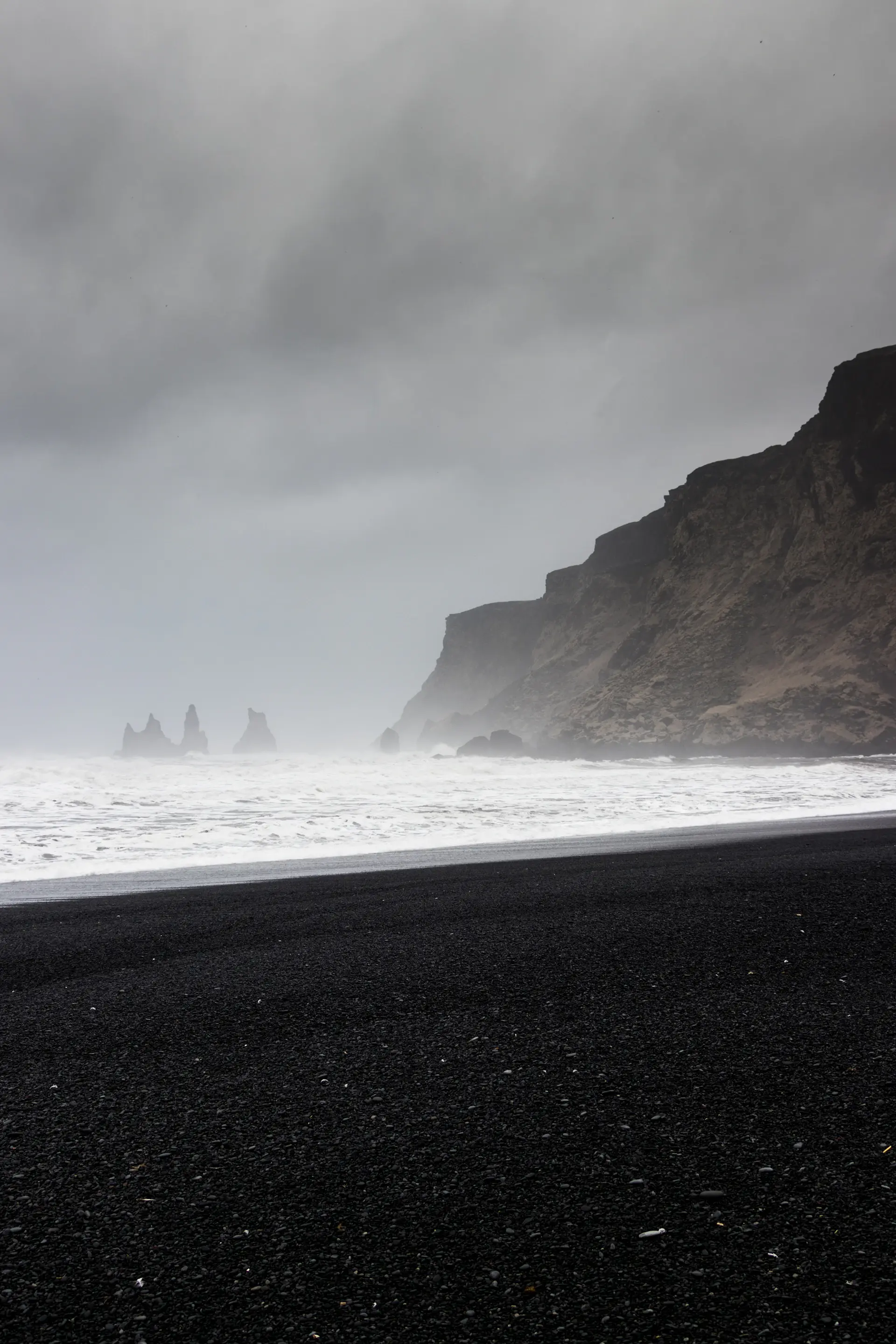 Foam sliding back across a black volcanic beach