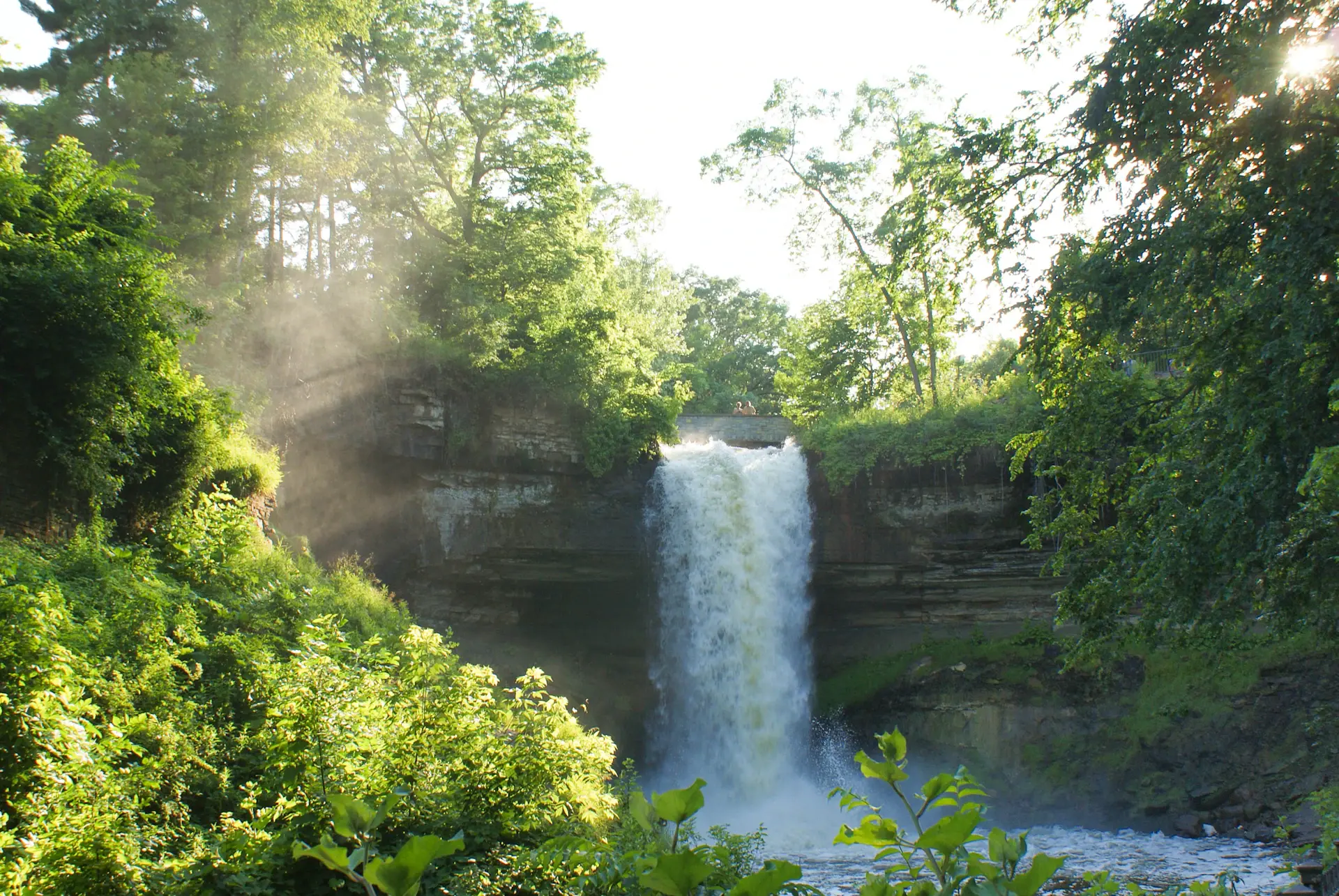 Sunlight catching the spray of a wide tiered waterfall at dawn