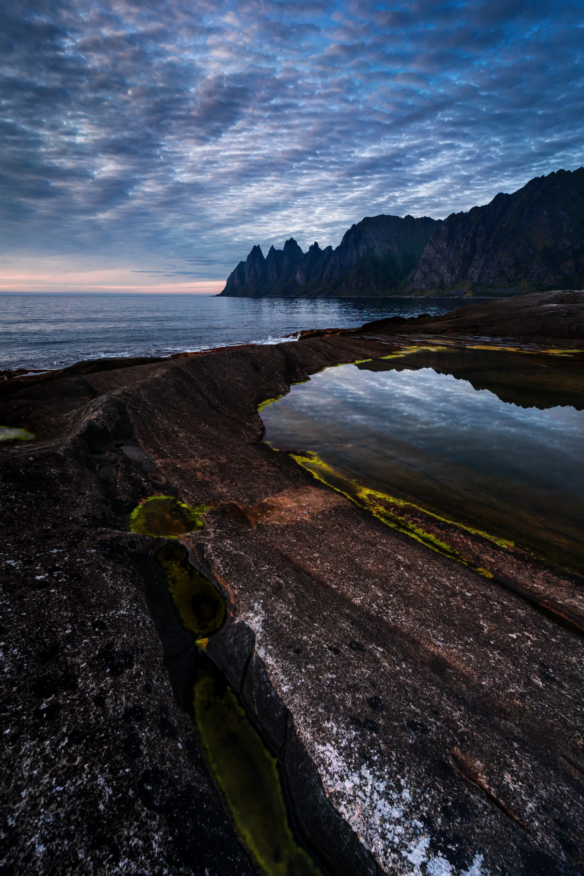 A deep fjord between steep dark cliffs at blue hour